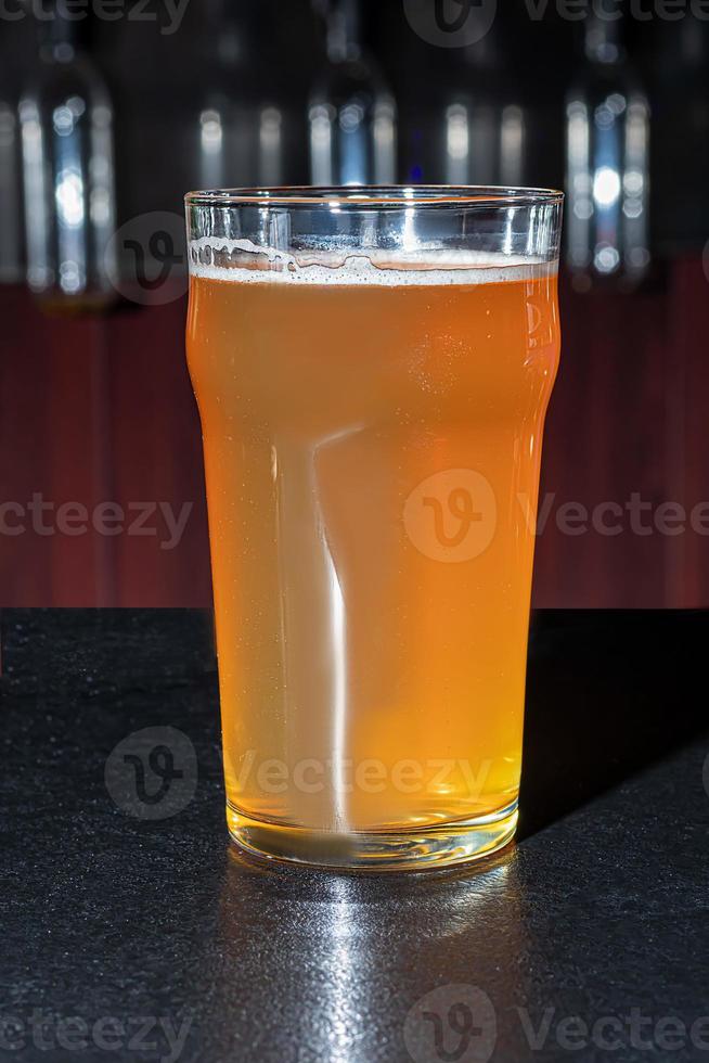 Glasses with different types of craft beer on a wooden bar. In glasses and bottles. Nuts and crackers on the table. On a dark background. photo