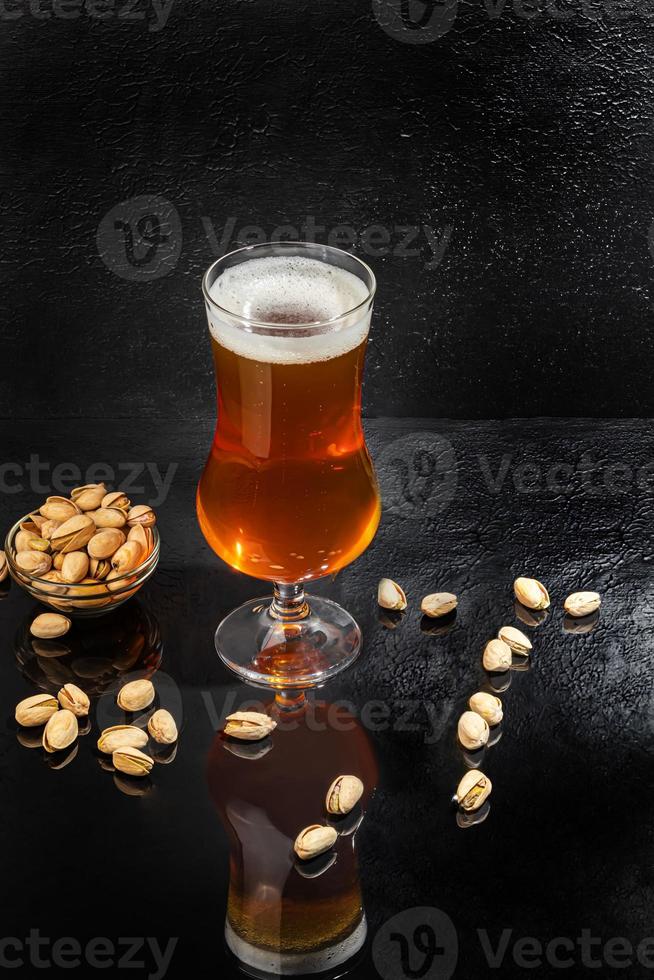 Glasses with different types of craft beer on a wooden bar. In glasses and bottles. Nuts and crackers on the table. On a dark background. photo