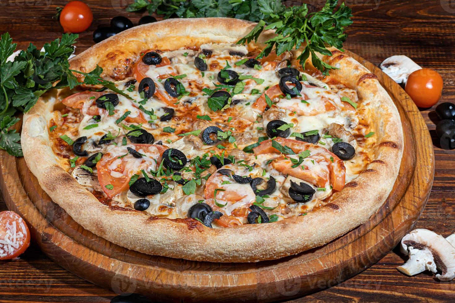 pizza con tocino y queso, hierbas y tomates cherry. con mozzarella, camarones y pulpos, mejillones y otros productos sobre un fondo de madera. foto