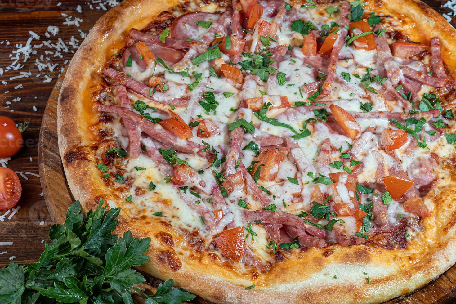 Pizza with bacon and cheese, herbs and cherry tomatoes. With mozzarella, shrimps and octopuses, mussels and other products on a wooden background. photo