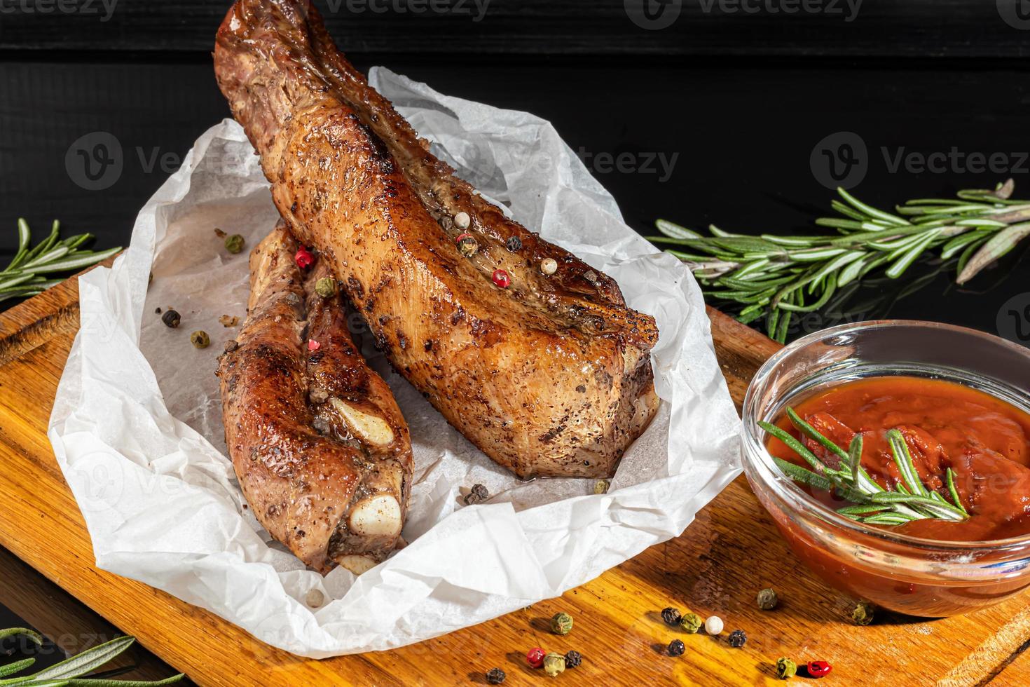 Meat dish on a plate with sauce. Chicken breast, fried pork. Parsley. Mustard sauces and ketchup. On a dark background. photo