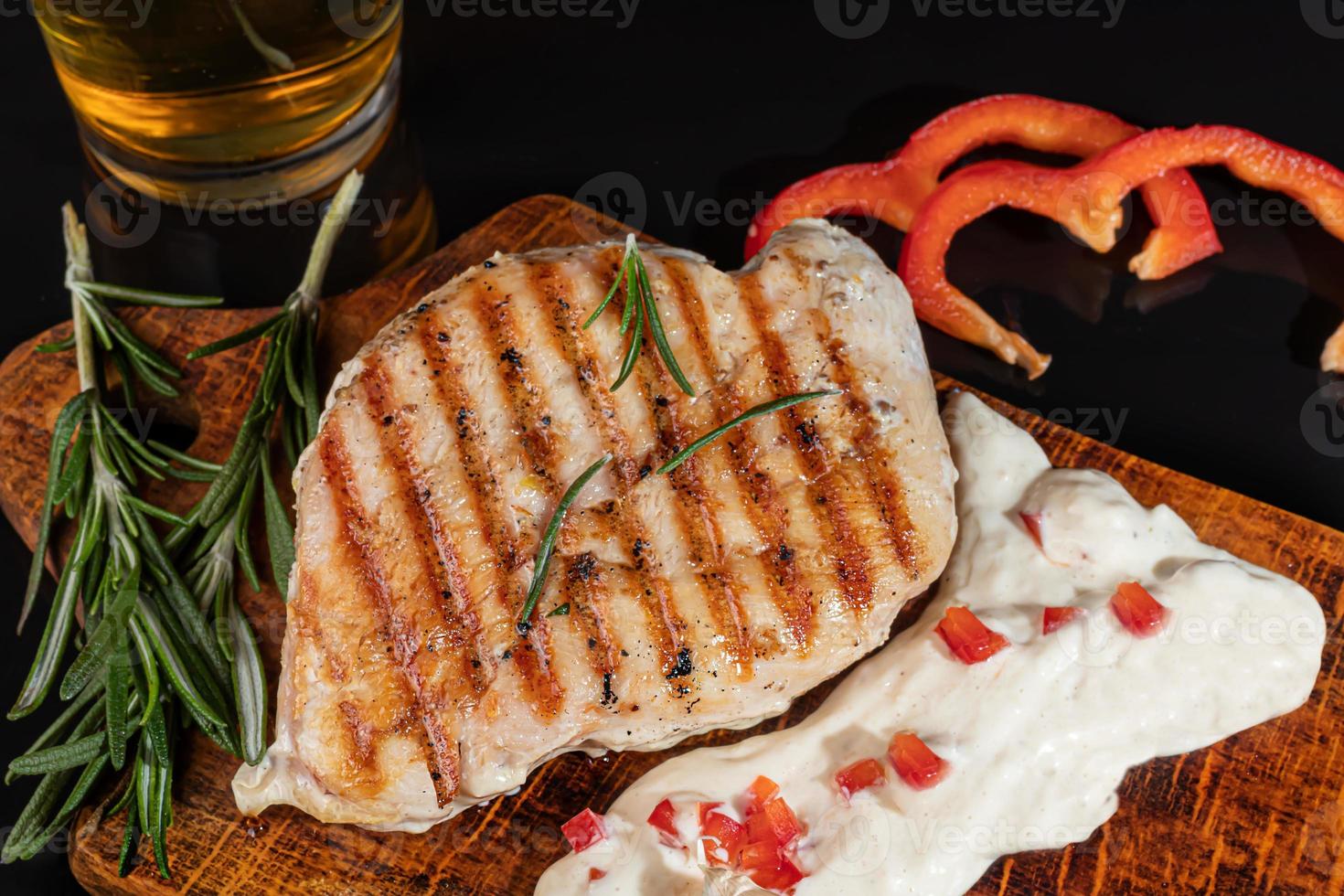 Meat dish on a plate with sauce. Chicken breast, fried pork. Parsley. Mustard sauces and ketchup. On a dark background. photo