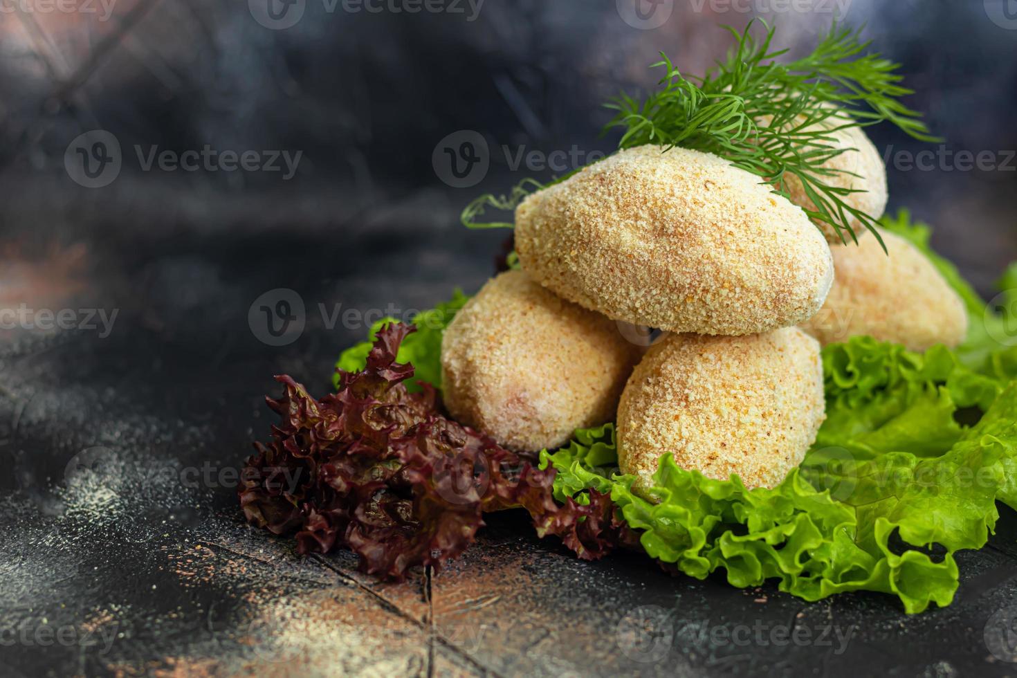 Semi-finished cutlets with breaded cheese or butter. Fast food preparation. On a dark background. photo