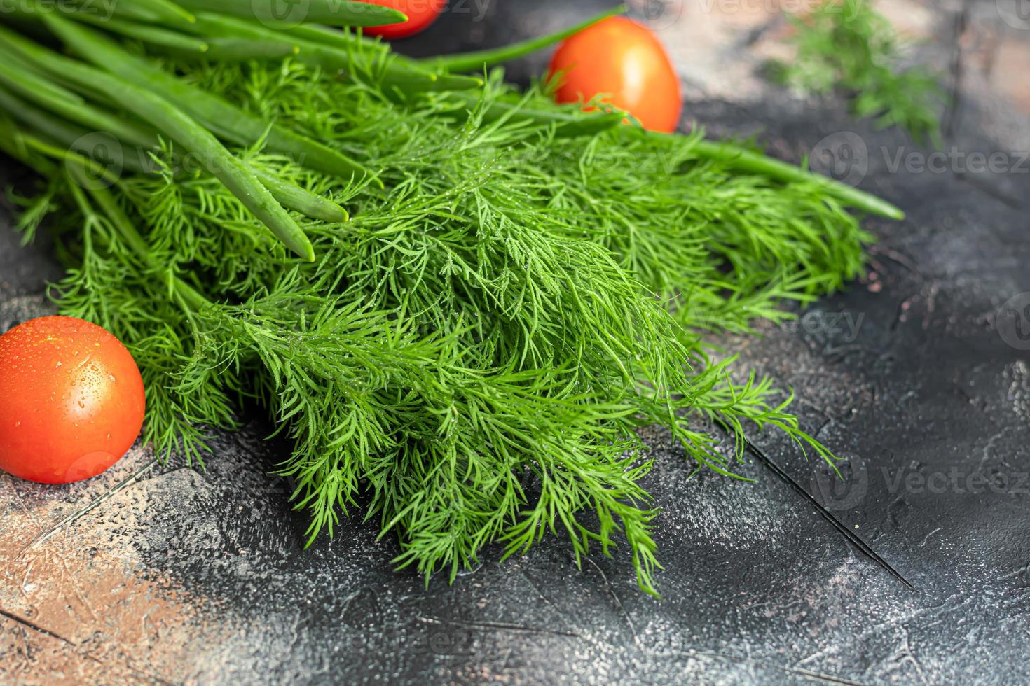 Fresh vegetables for salad. Tomatoes and lettuce, cucumbers with zucchini and cabbage with dill. Spring harvest, benefits and vitamins. On a dark background. photo