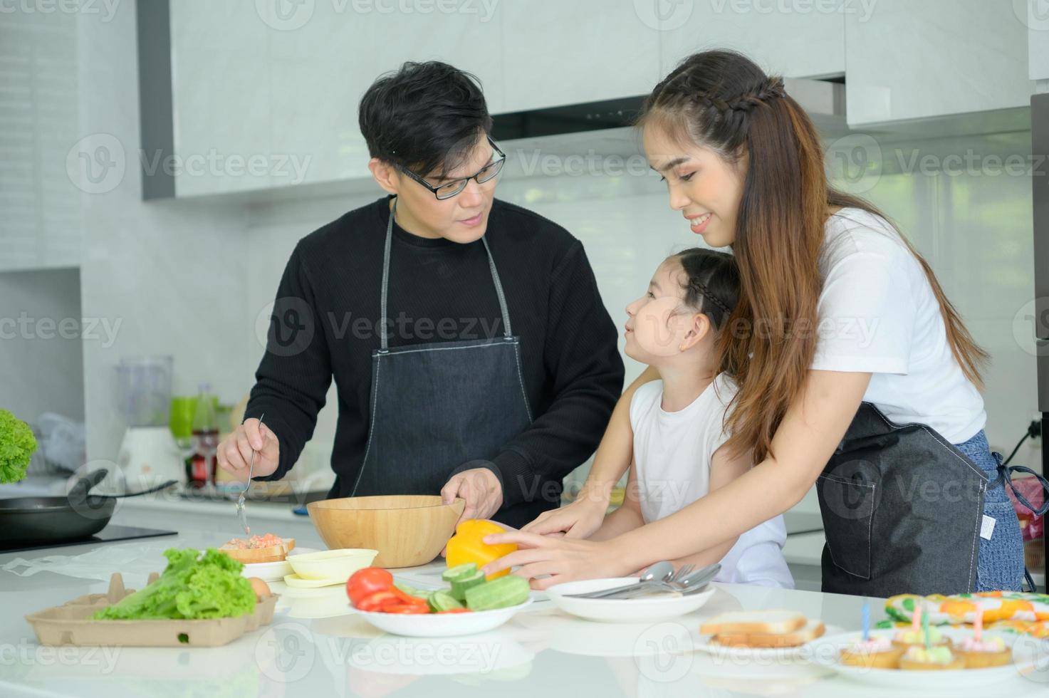 familia asiática que están cocinando juntos felizmente en la cocina de la casa. foto