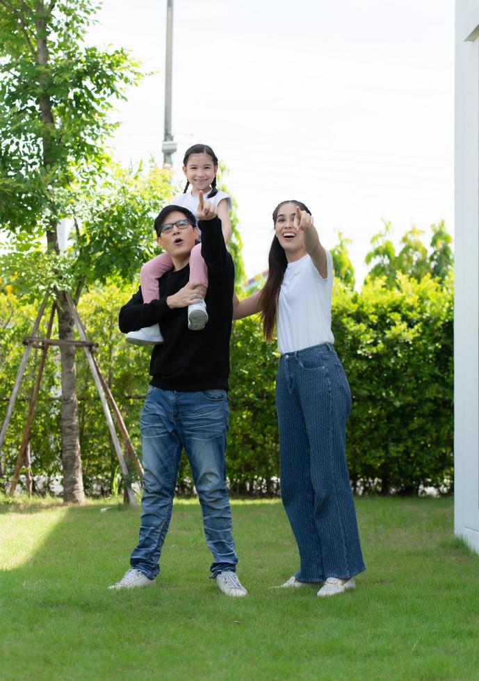 Asian family with both father, mother and daughter having fun in the garden of the house happily photo
