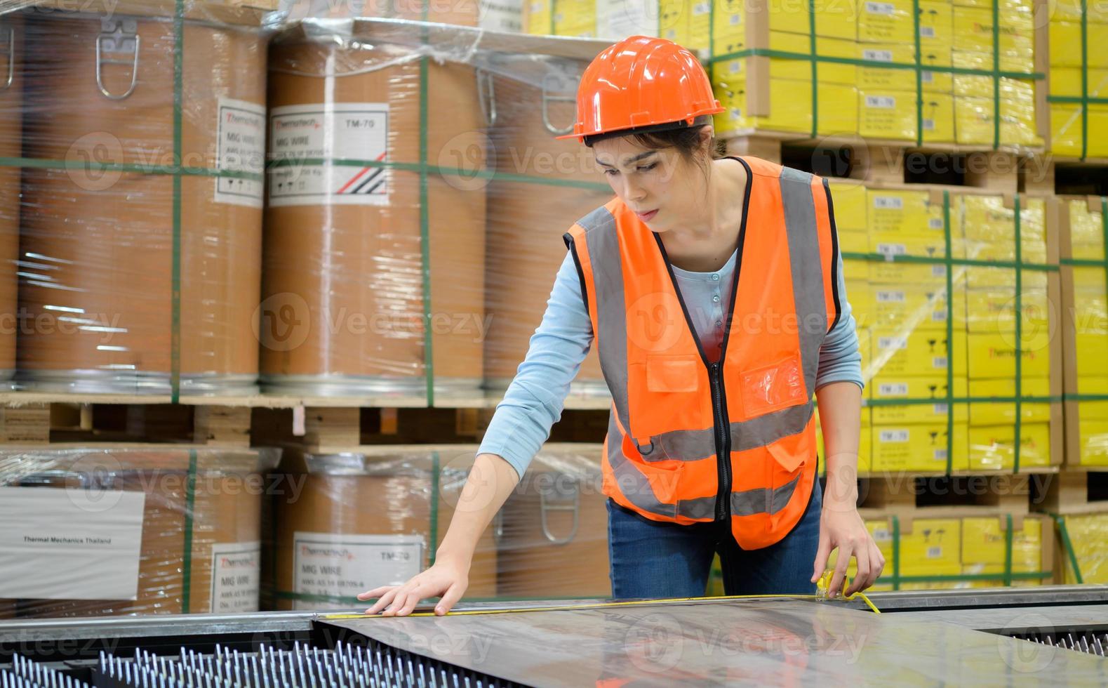 A female worker is measuring the size of a sheet steel cut from a steel cutter. photo