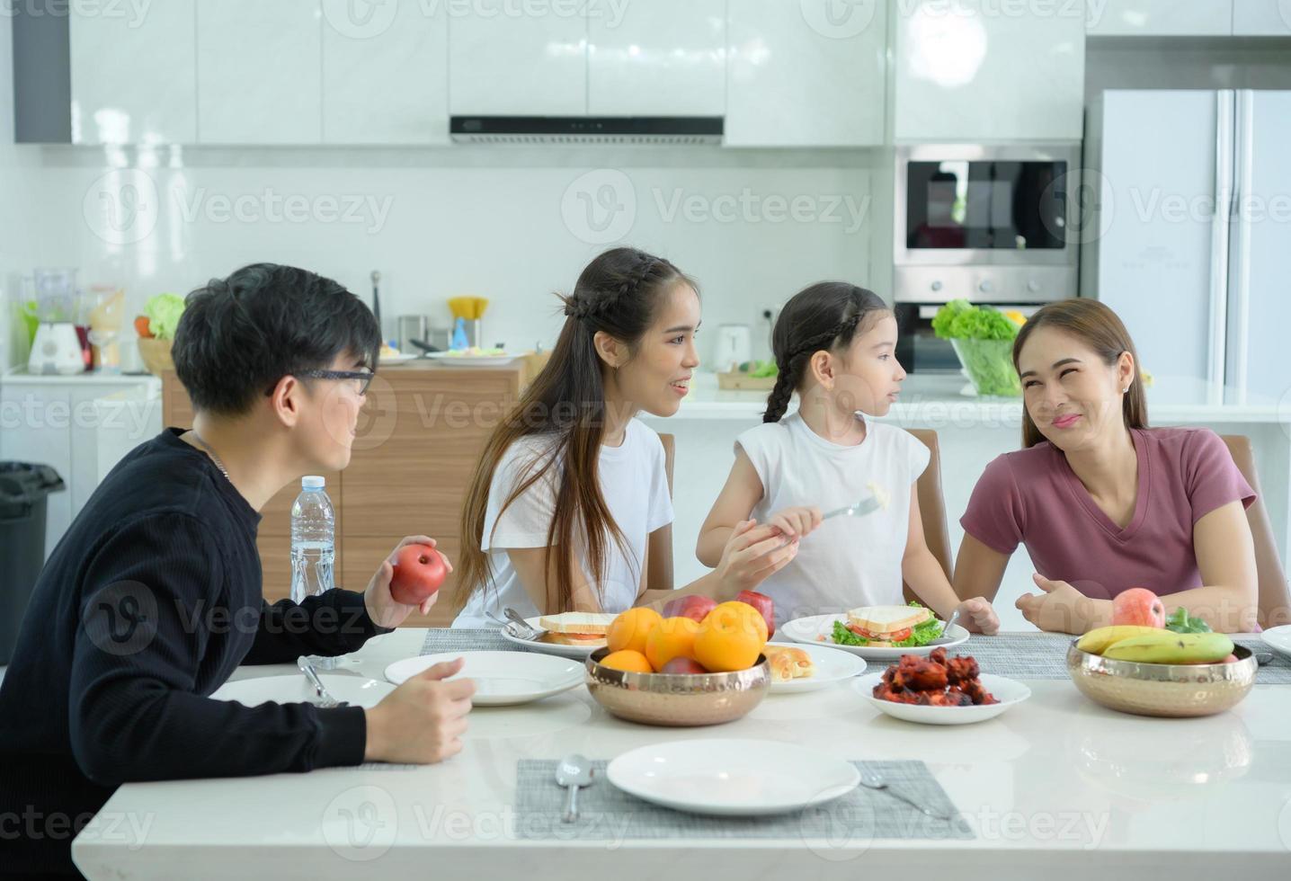 familia asiática están desayunando juntos felizmente en el comedor de la casa. foto