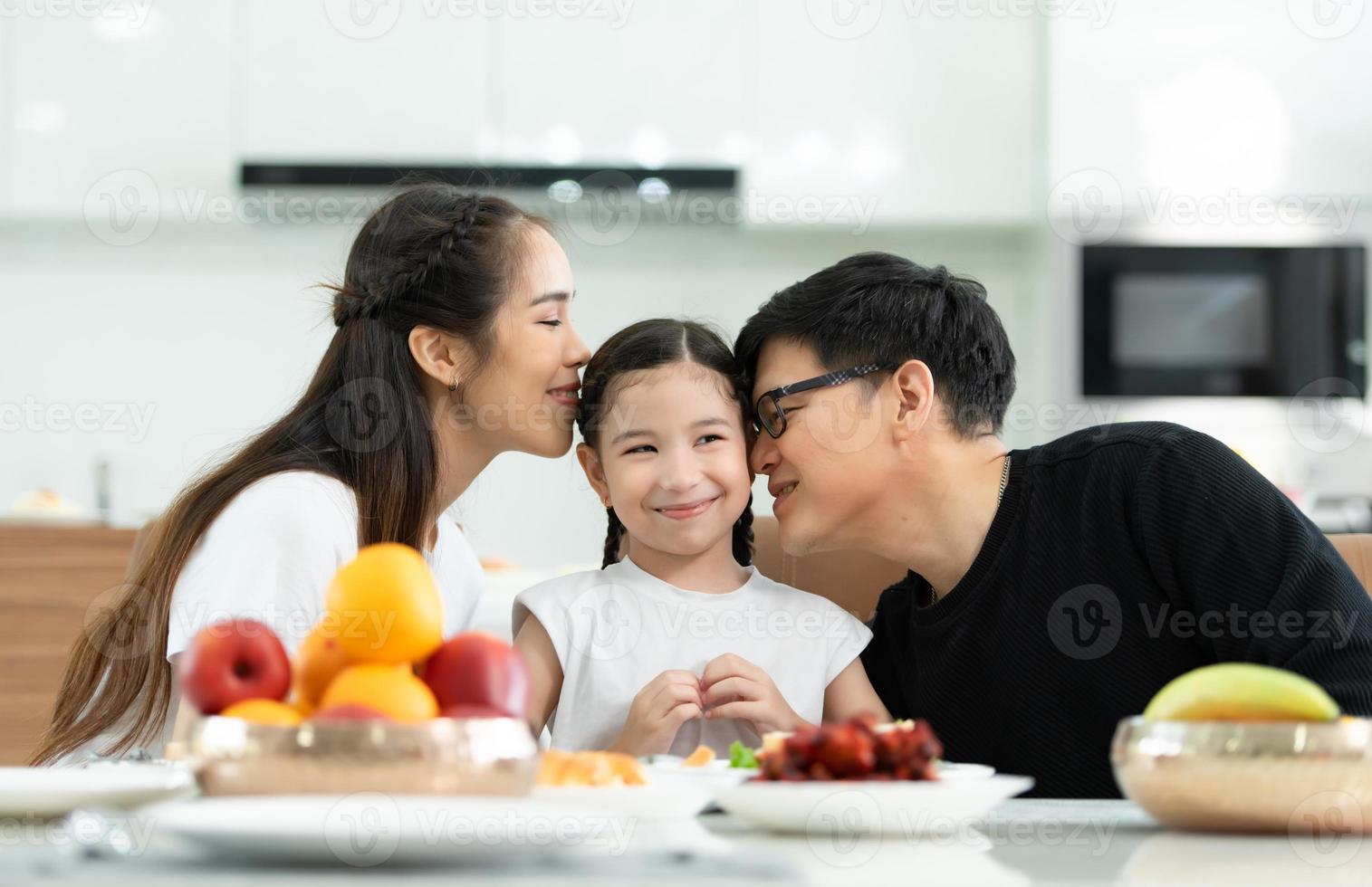 el padre y la madre asiáticos muestran su amor a la pequeña hija y desayunan juntos felizmente en el comedor de la casa. foto