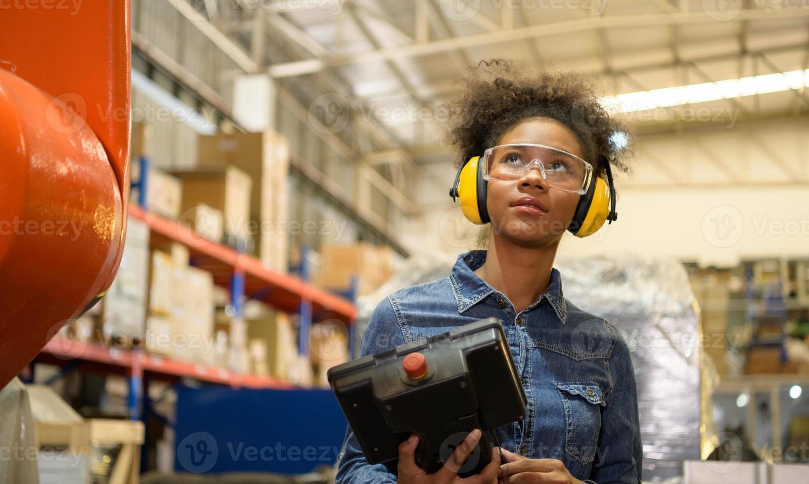 A young female worker is controlling a mechanical robot. to sort out the items that come into the warehouse to wait for the next shipment. photo