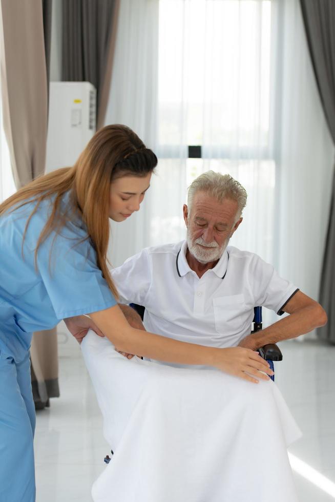 The doctor puts on a blanket to warm himself up and talks to an elderly patient with depression. in the living room of the house photo