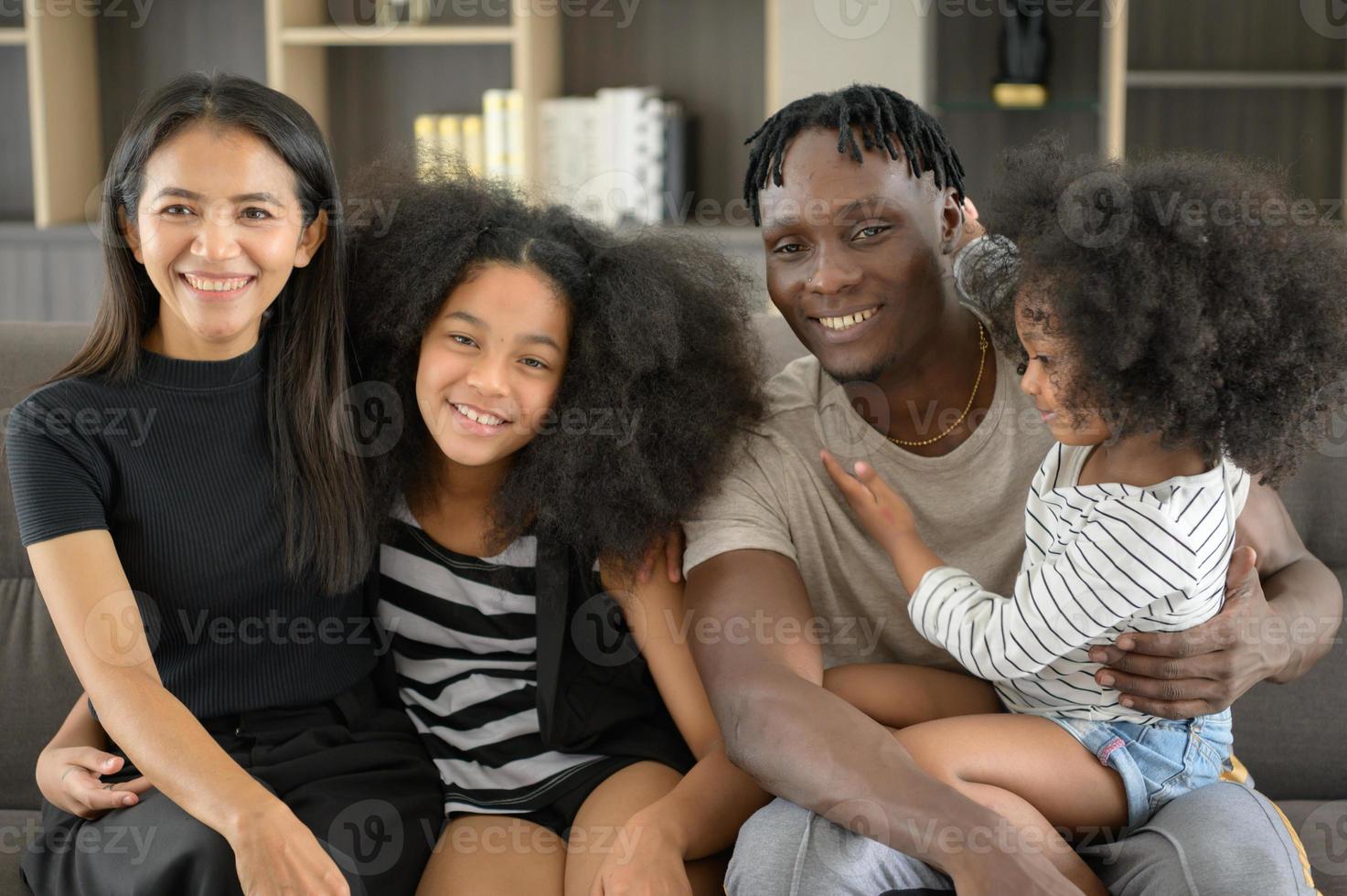 Asian-African American family relaxing, chatting, painting and having fun on vacation in the living room of the house photo