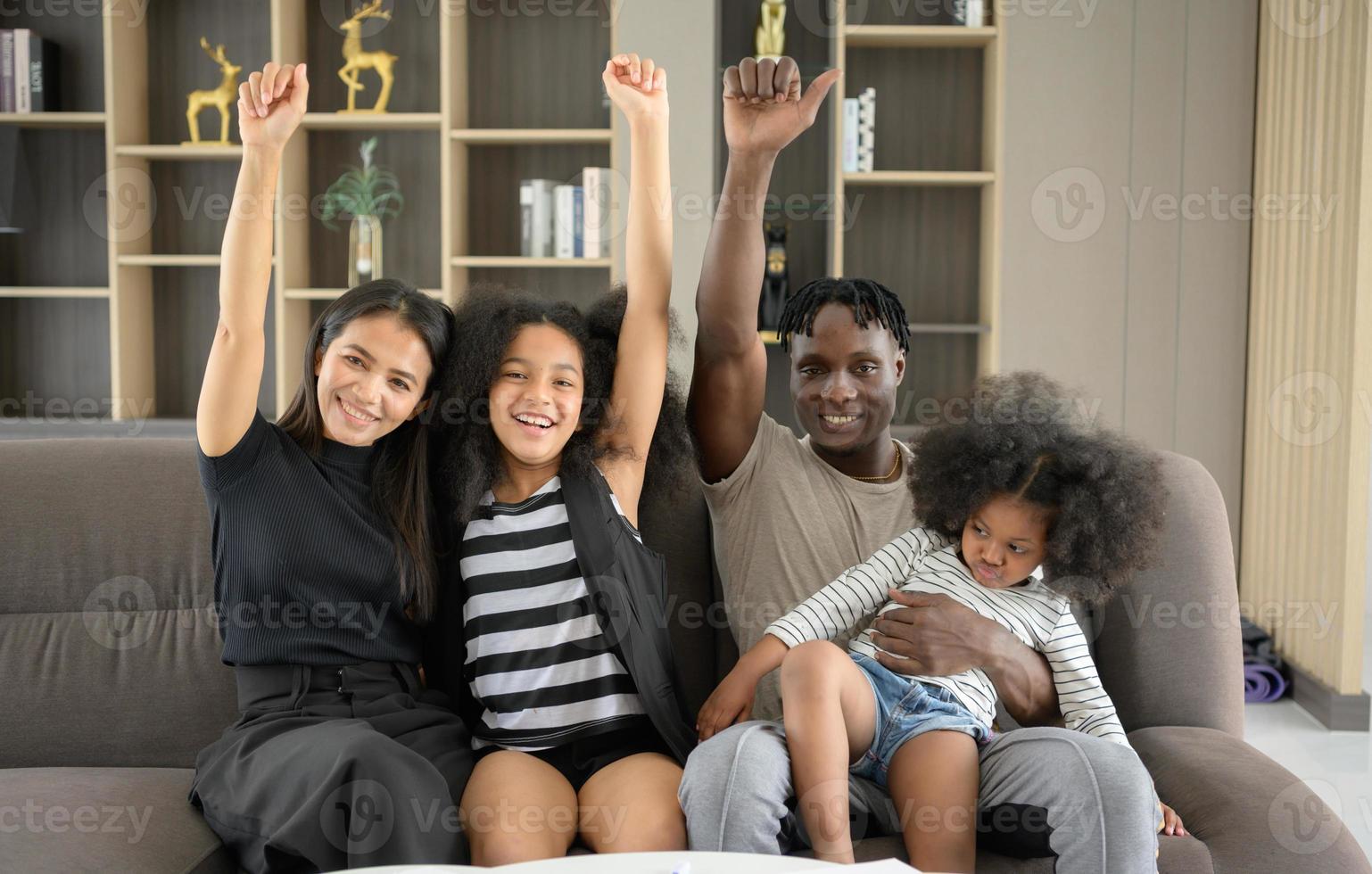 Asian-African American family relaxing, chatting, painting and having fun on vacation in the living room of the house photo