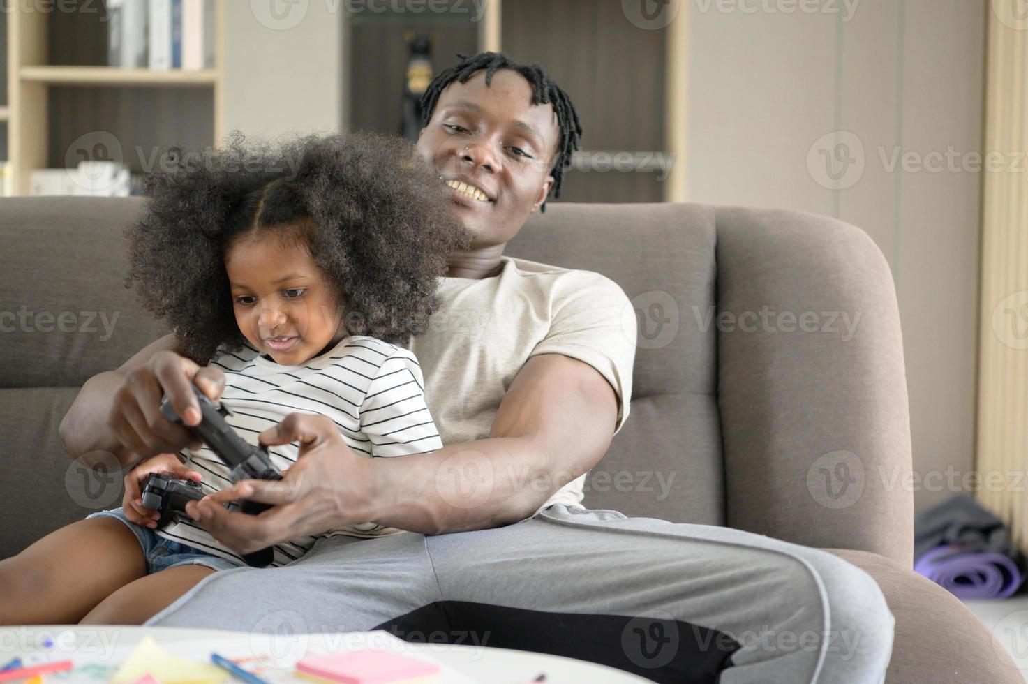 Asian-African American father and son relax by playing computer games in the living room of the house. photo