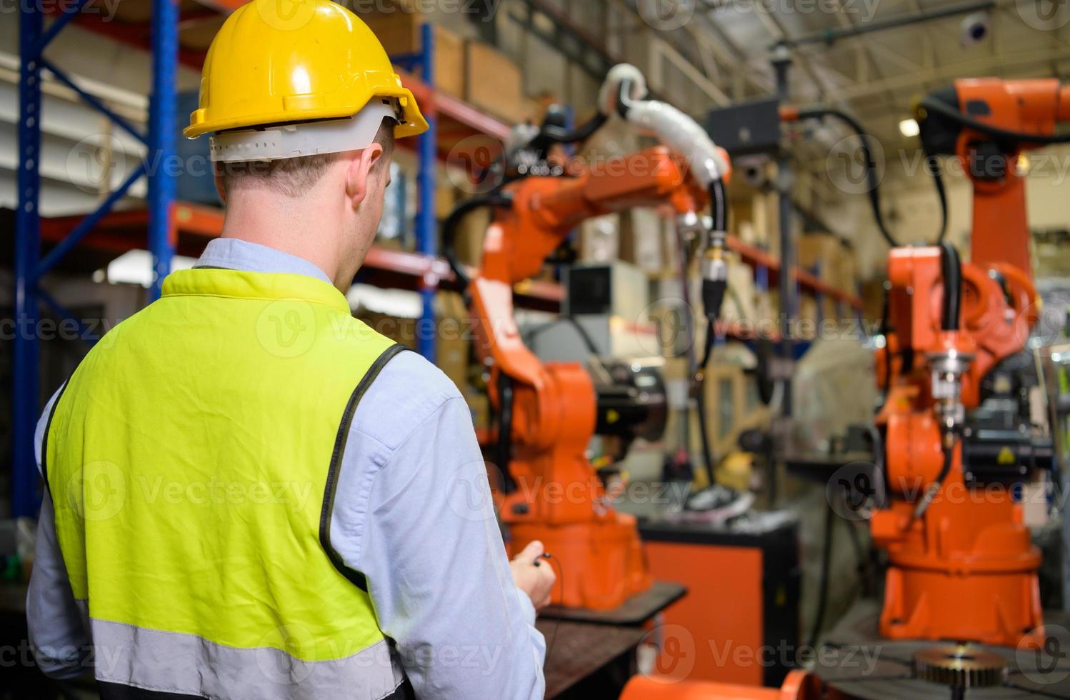A male worker is controlling a welding robot. by using forcing welding with a control screen which is used for precision welding control. Fast and highly secure photo
