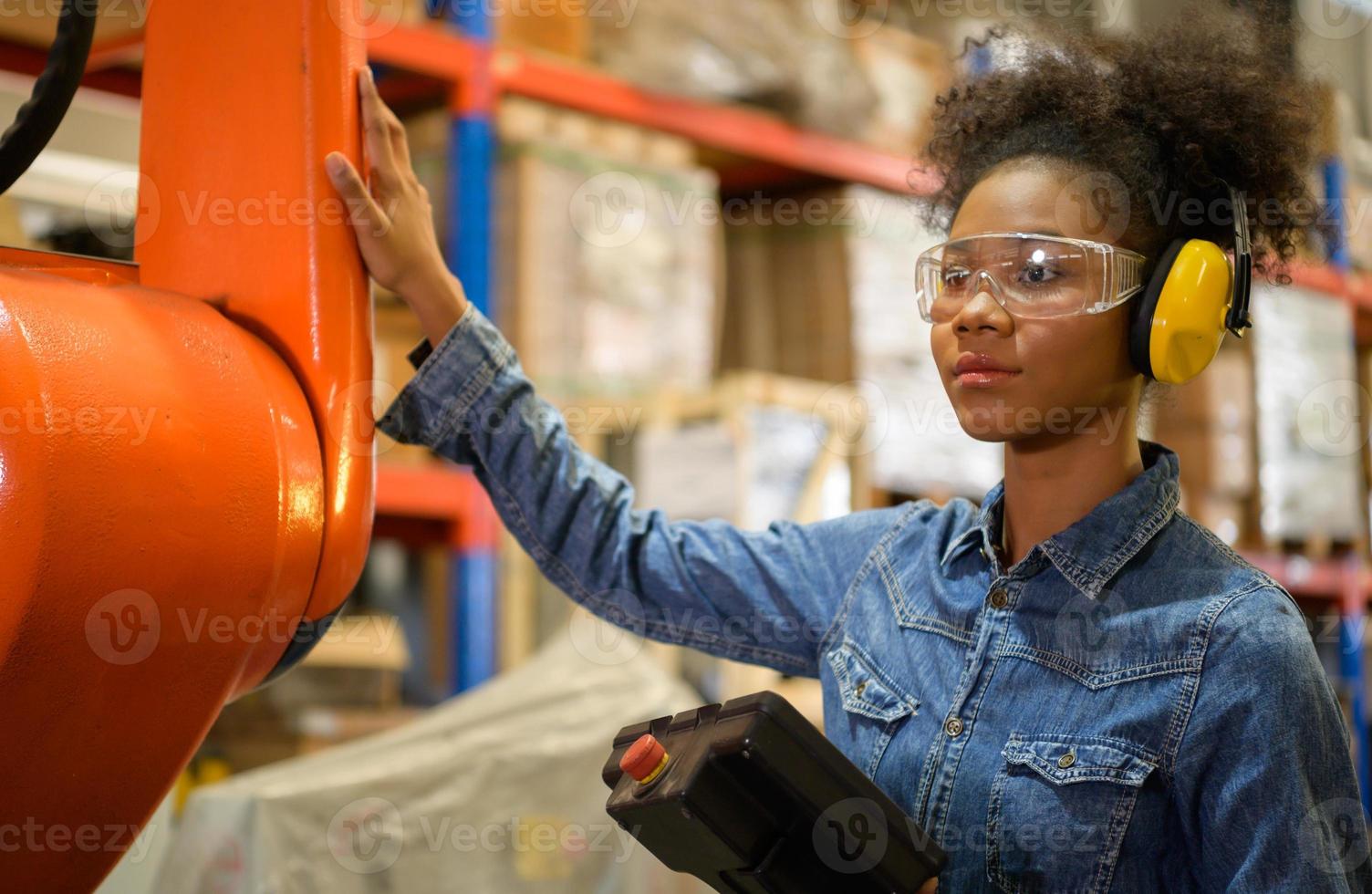 A young female worker is controlling a mechanical robot. to sort out the items that come into the warehouse to wait for the next shipment. photo