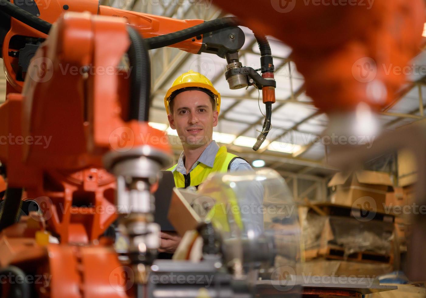 un ingeniero masculino revisando el funcionamiento de un robot de soldadura. utilizado para control de soldadura de precisión rápido y muy seguro foto