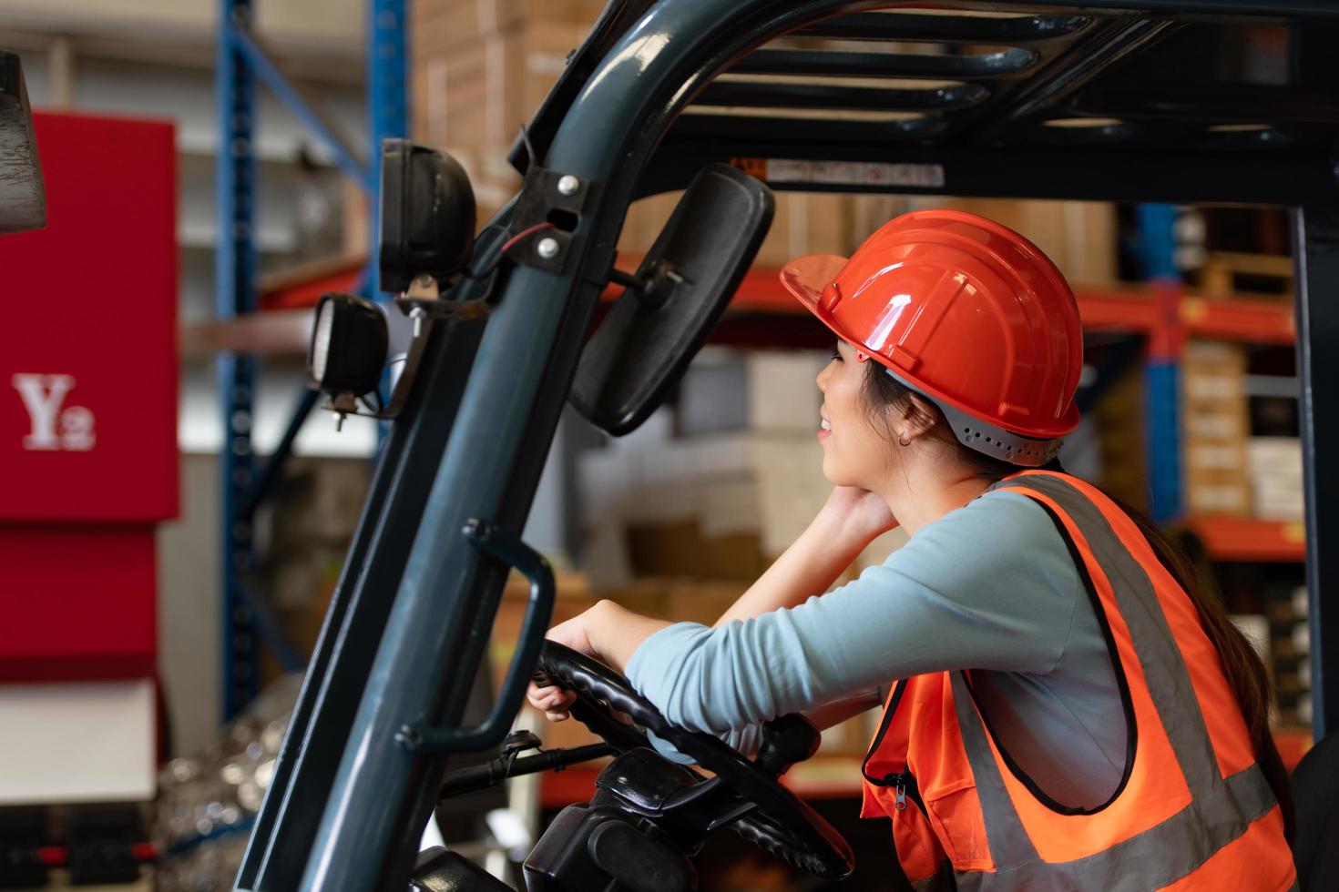 Portrait of an Asian woman with a forklift used to lift heavy objects in a warehouse. photo