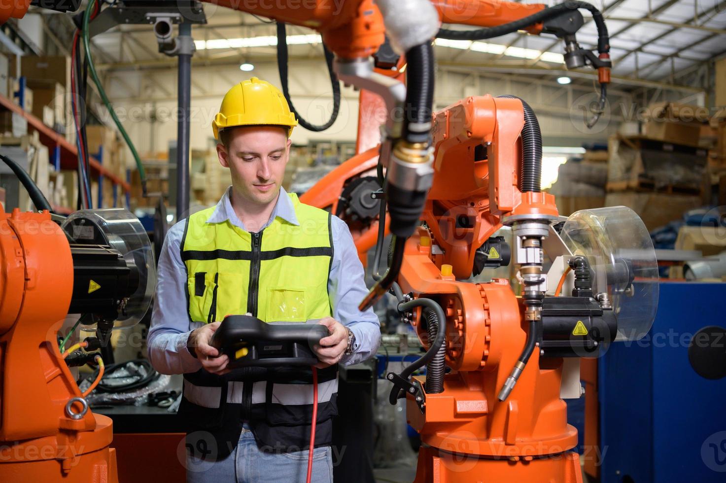 A male worker is controlling a welding robot. by using forcing welding with a control screen which is used for precision welding control. Fast and highly secure photo