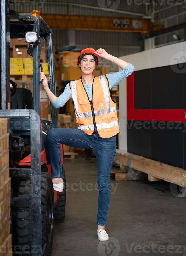 Portrait of an Asian woman with a forklift used to lift heavy objects in a warehouse. photo