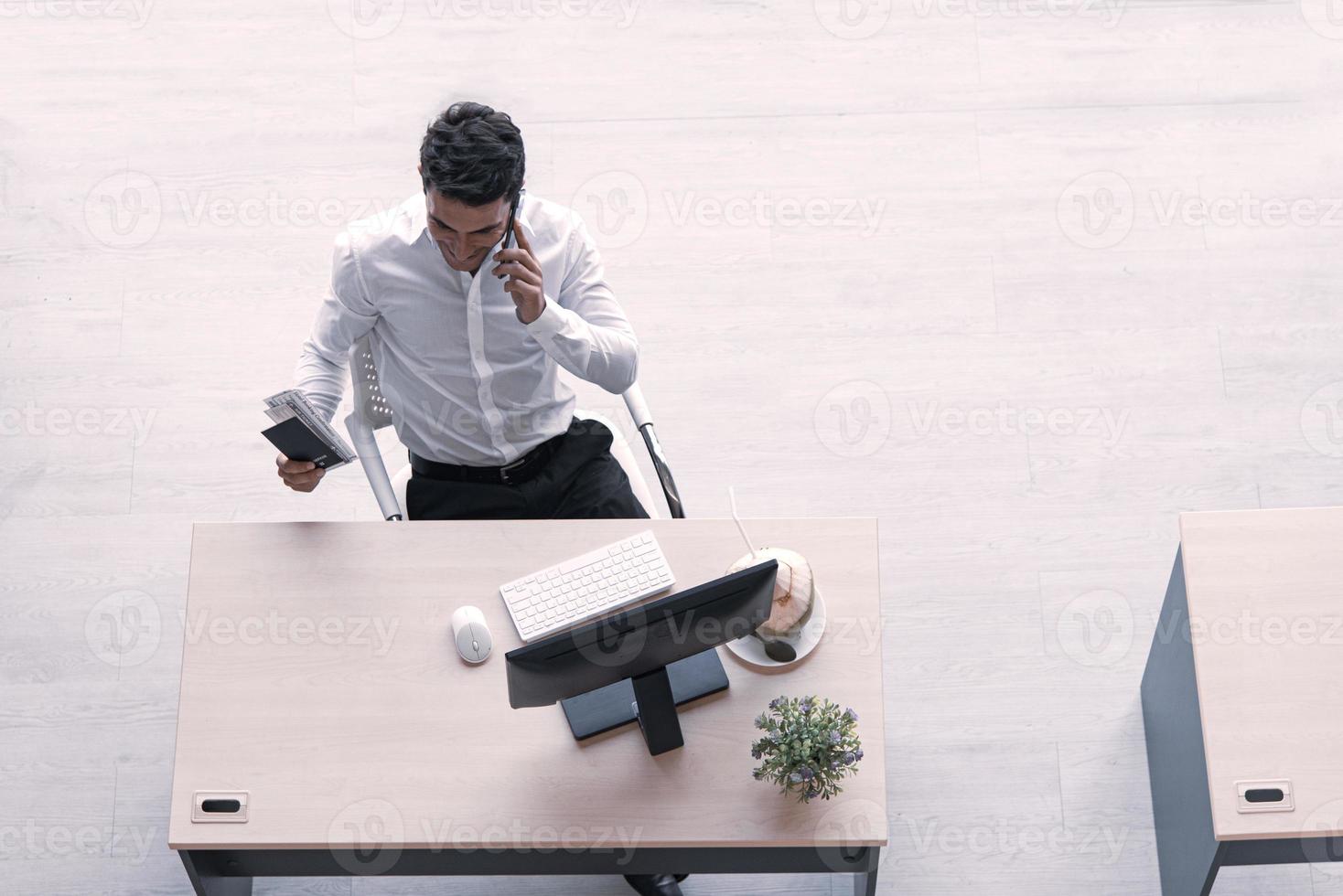 vista superior del ejecutivo, gerente o ingeniero bebiendo jugo de coco trabajando en una computadora usando un teléfono inteligente en una oficina creativa de distanciamiento social. foto
