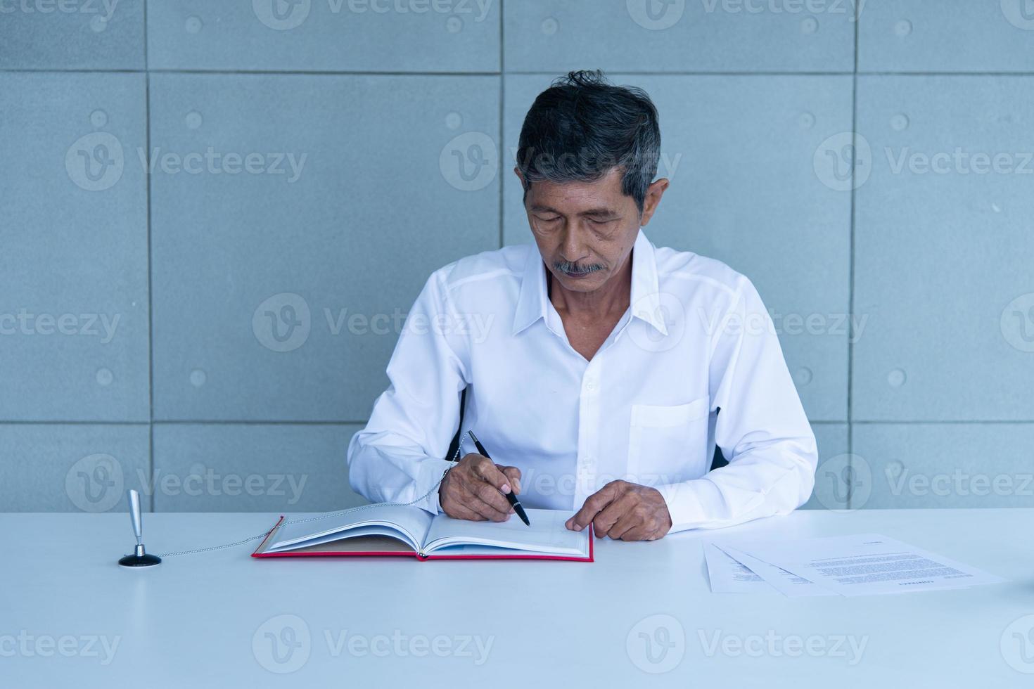Work from home and social distancing concept. Asian business old man  working at co-working space or meeting room. Aging man sign signature. photo