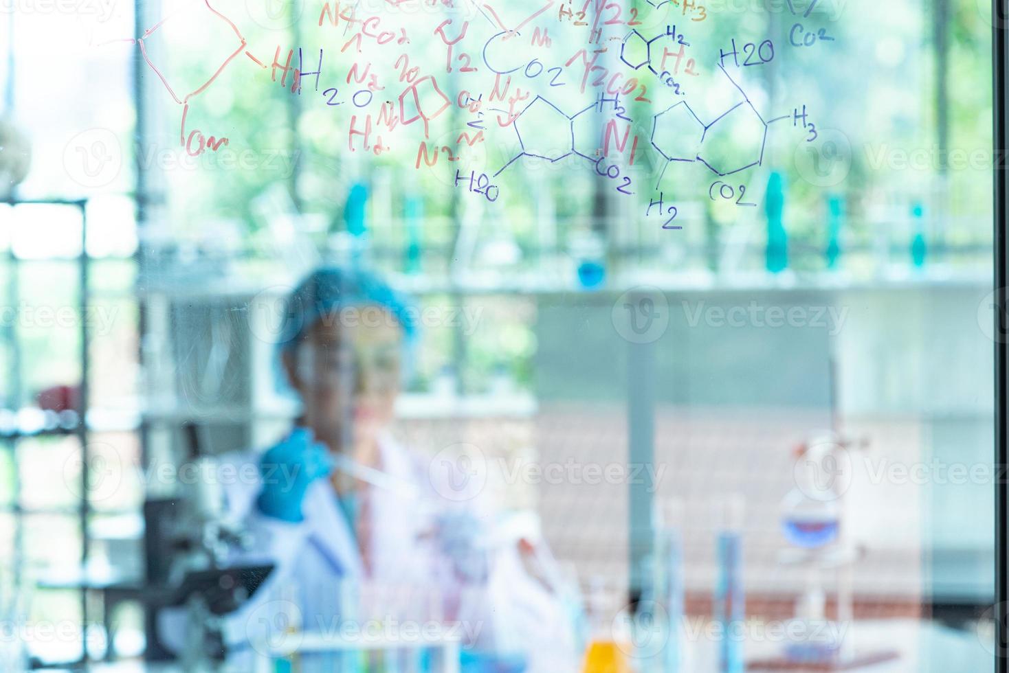 Blur Asian woman scientist, researcher, technician, or student conducted chemistry research and sitting after  glass board in laboratory photo