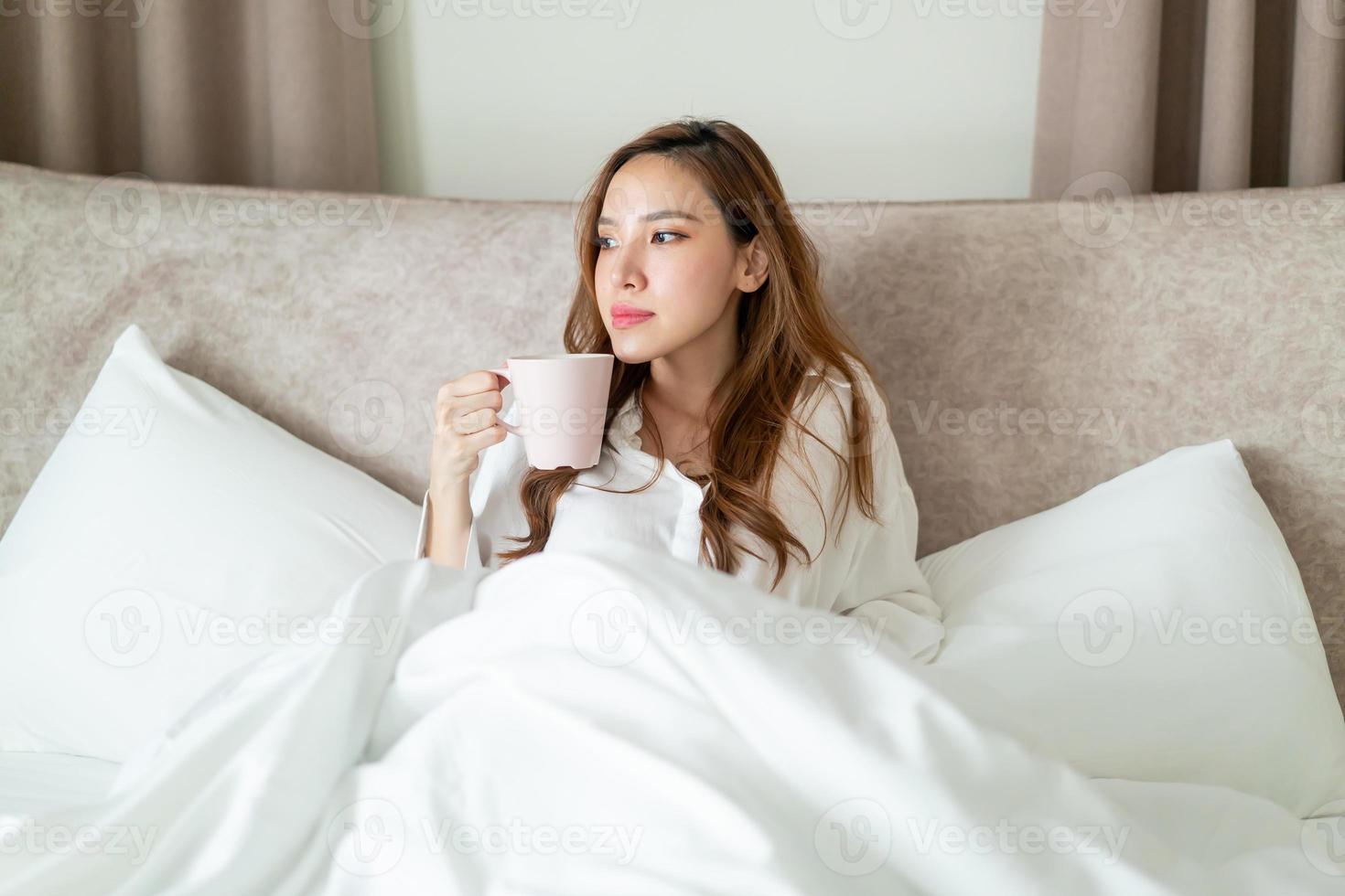 retrato, mujer hermosa, despertar, y, tenencia, taza de café, o, taza, en cama foto