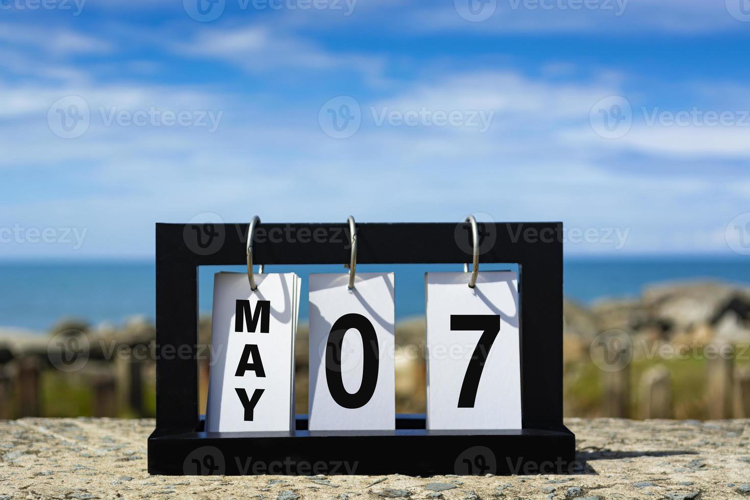 May 07 calendar date text on wooden frame with blurred background of ocean. photo