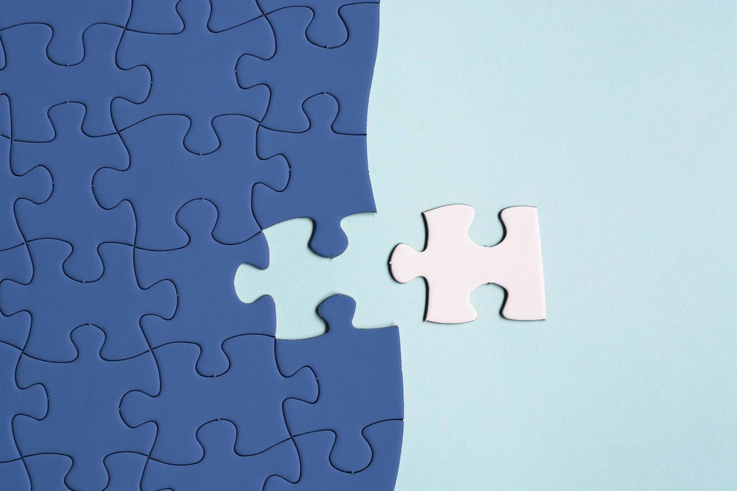 Dark blue jigsaw puzzle with some missing pieces on blue background. Flat lay. photo