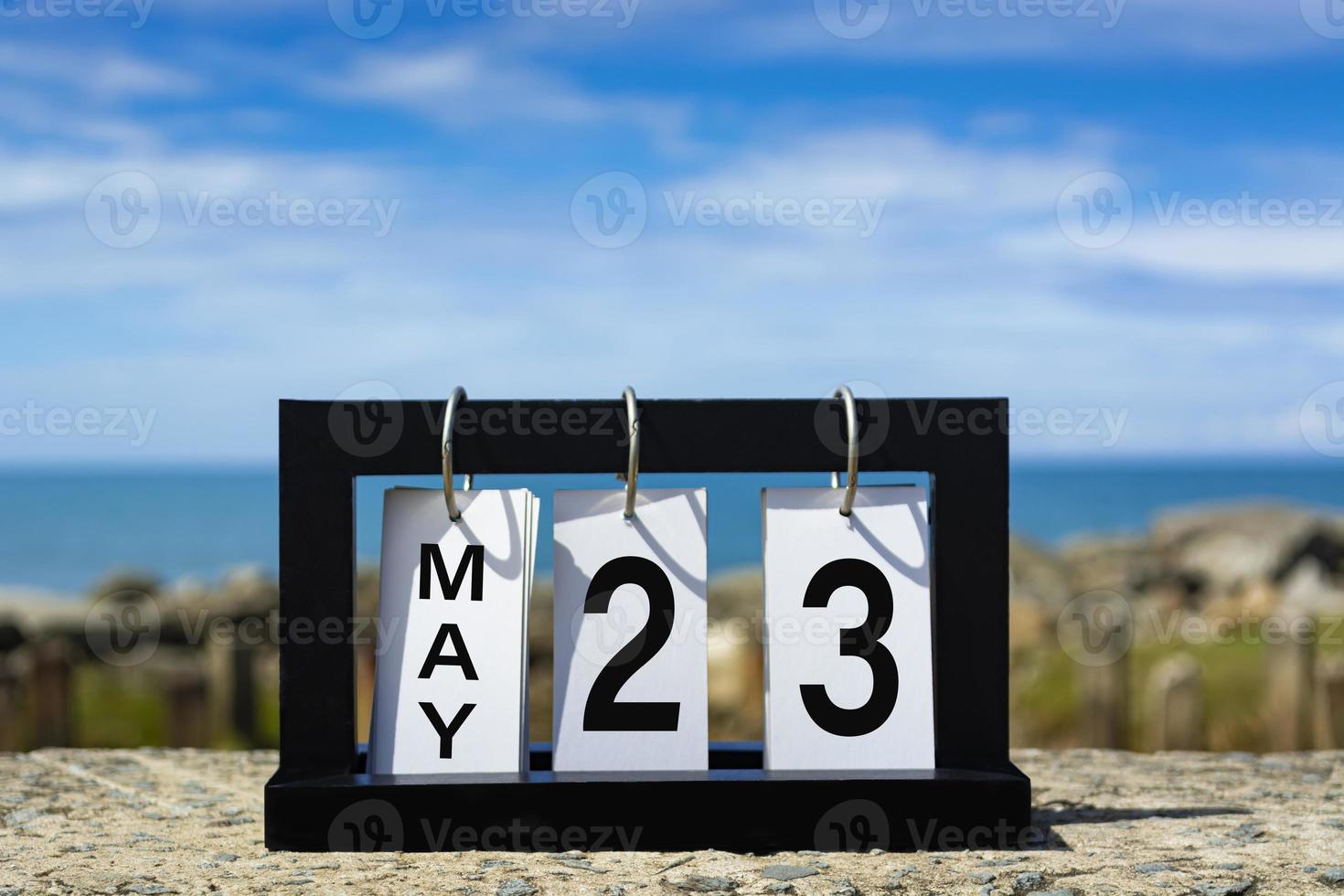 23 de mayo texto de fecha de calendario en marco de madera con fondo borroso del océano. foto