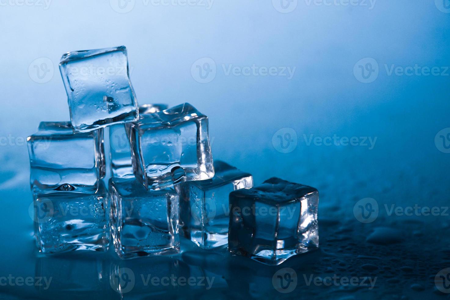 cubitos de hielo sobre fondo azul de estudio. el concepto de frescura con frialdad de cubitos de hielo. foto