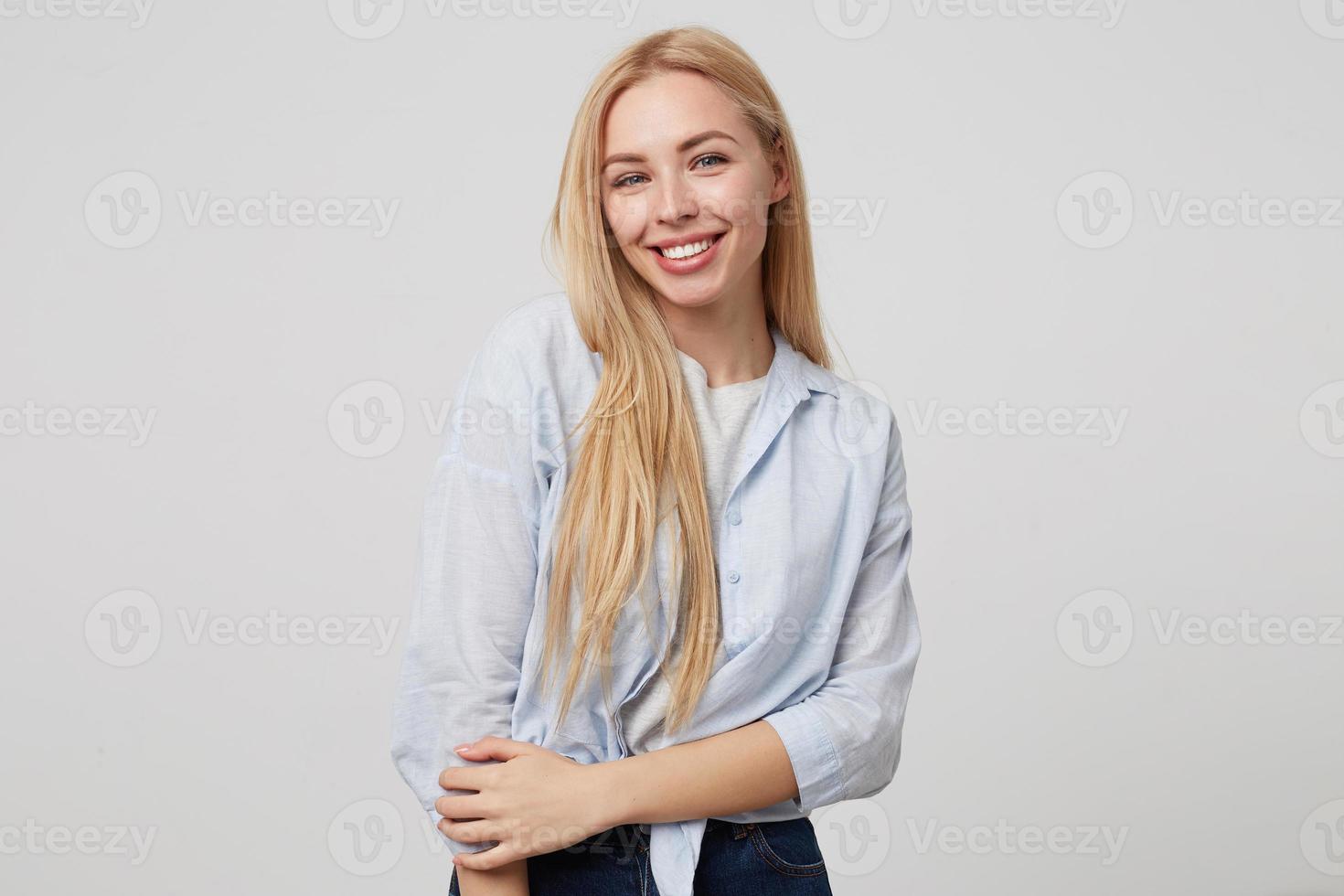 Indoor portrait of young attractive blonde long haired woman smiling to camera sincerely, posing over white background, wearing jeans and blue shirt 9247779 Stock Photo at Vecteezy Indoor portrait of young attractive blonde long haired woman smiling to camera sincerely, posing over white background, wearing jeans and blue shirt 9247779 Stock Photo at Vecteezy