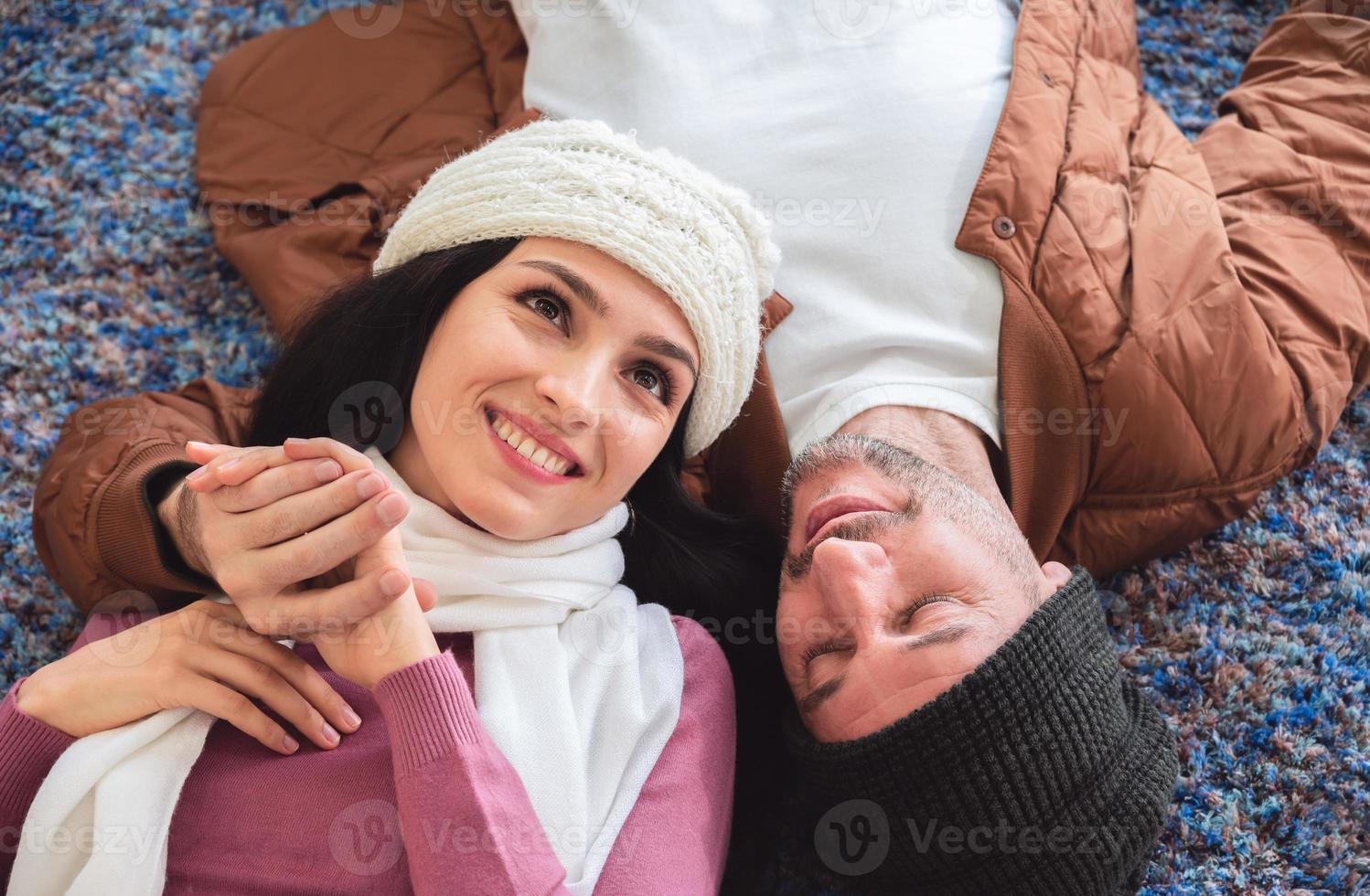 hombre y mujer tirados en el suelo. pareja sonriente relajándose en casa foto