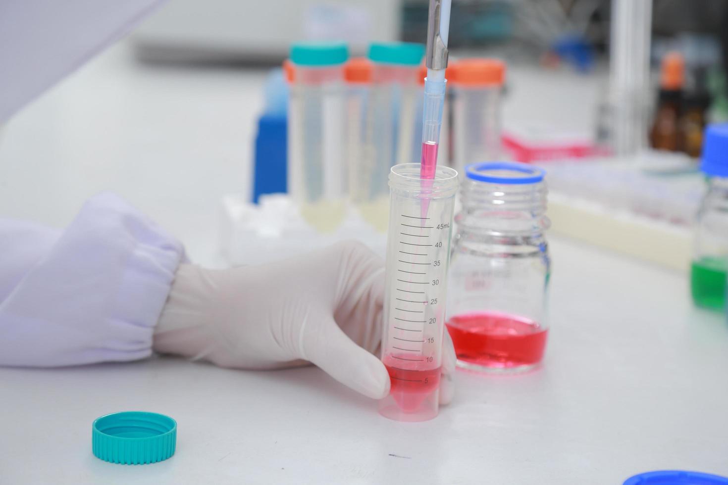 Woman scientist biochemist at the workplace makes the analysis in the modern laboratory. She is holding a dropper and a test tube photo