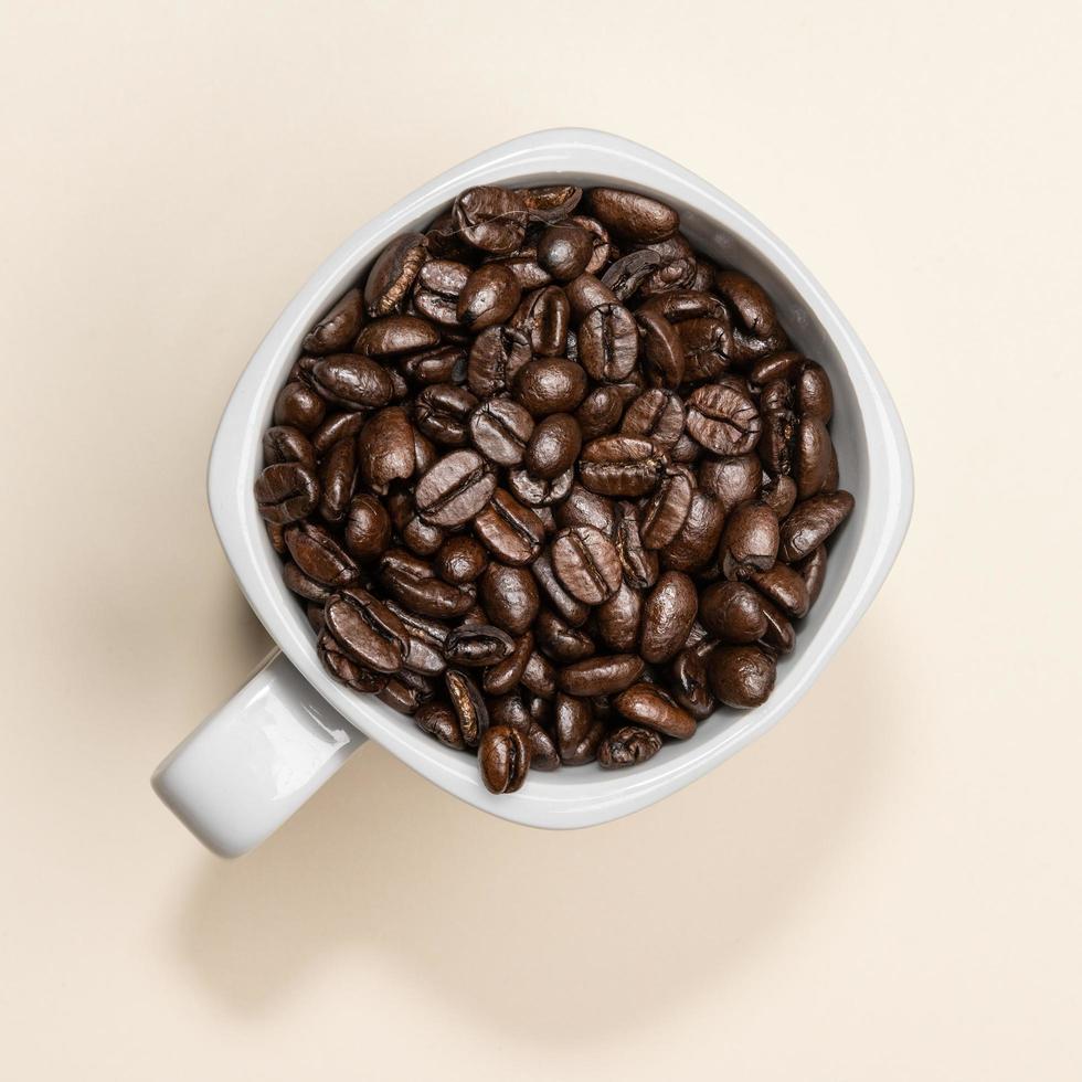 Coffee beans in white cup on coloured background photo