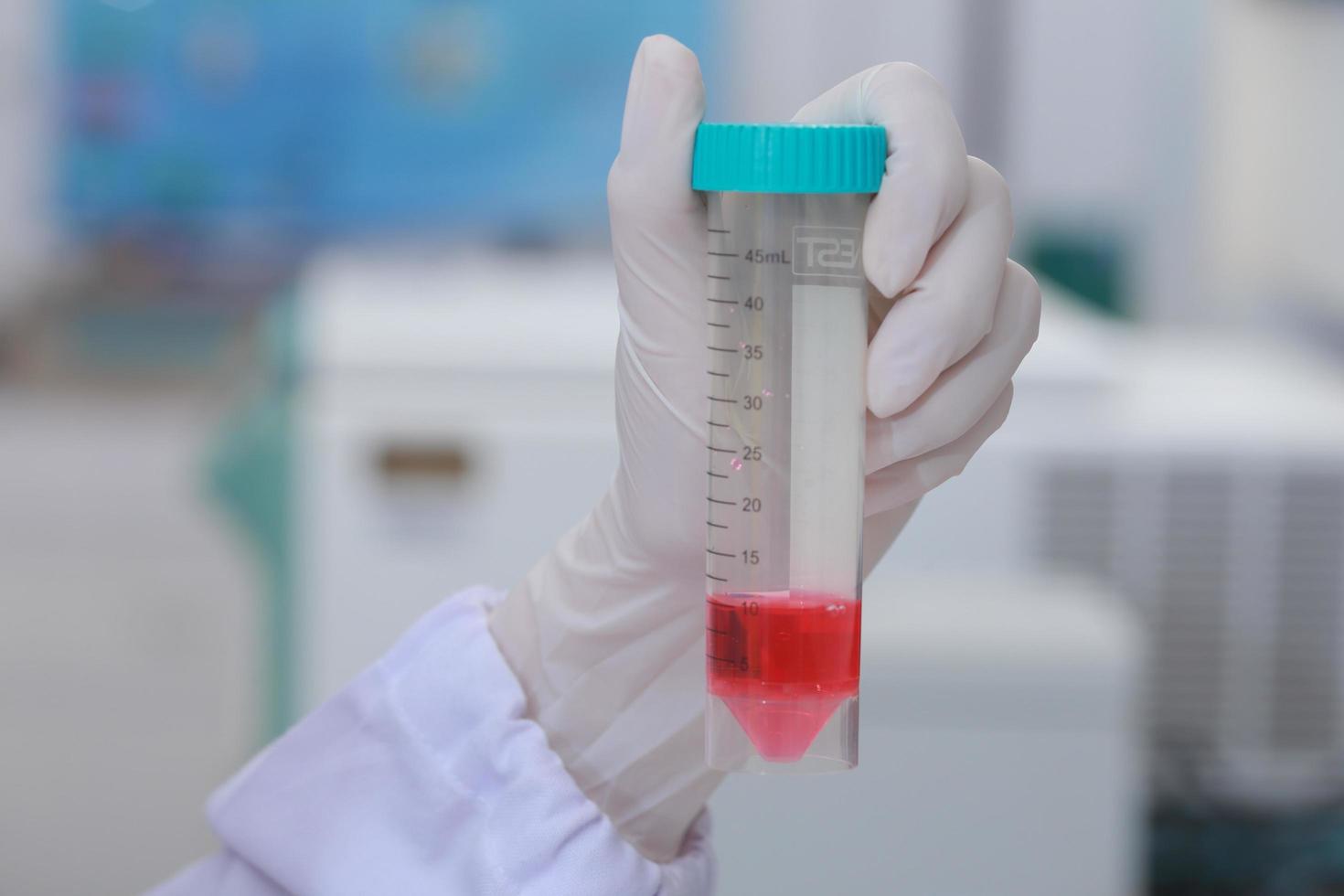 Woman scientist biochemist at the workplace makes the analysis in the modern laboratory. She is holding a dropper and a test tube photo