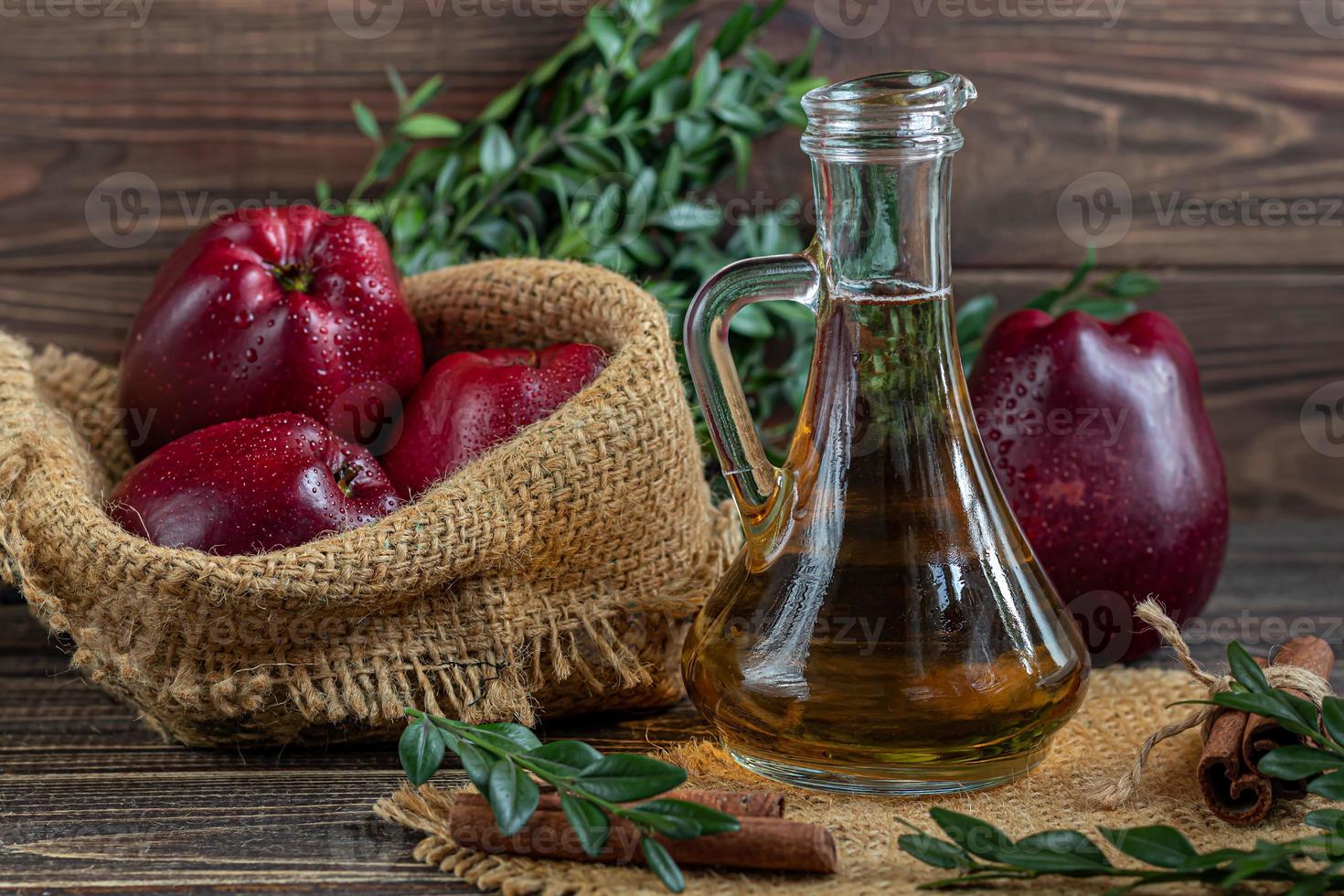 Apple cider vinegar and red apples on a dark, wooden background. Selective focus. fermented product. Healthy food. photo