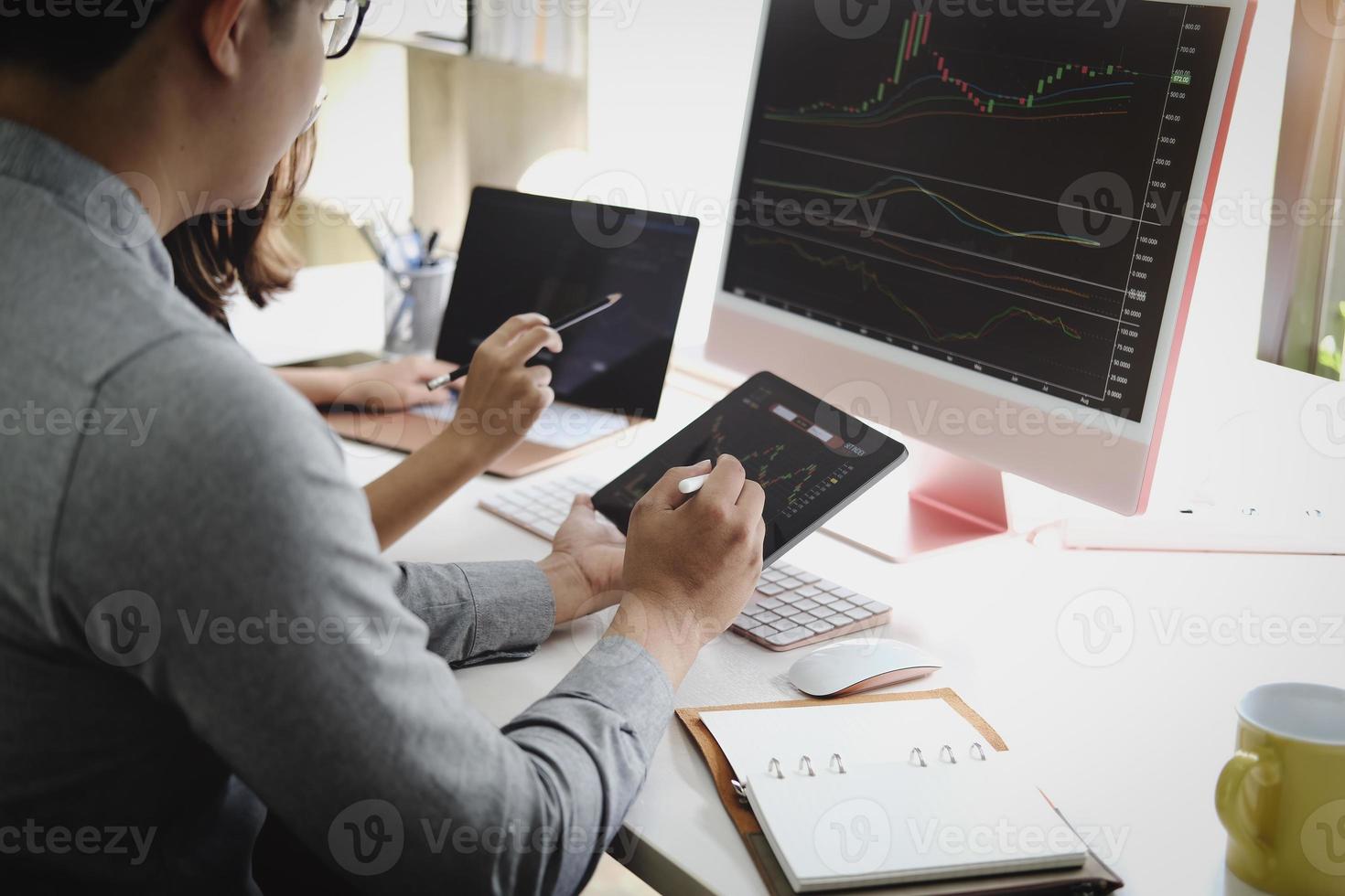 An investment expert points a pen at a computer monitor to analyze the stock market to teach you how to make a profit. photo