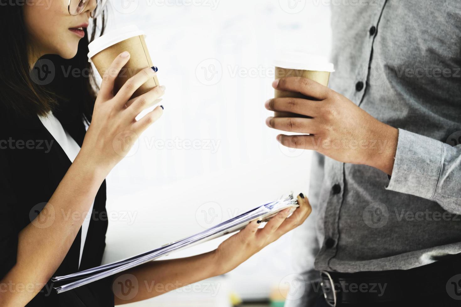 concéntrese en la mano de una mujer sosteniendo una taza de café y charlando con un compañero de trabajo durante el descanso de la tarde. foto