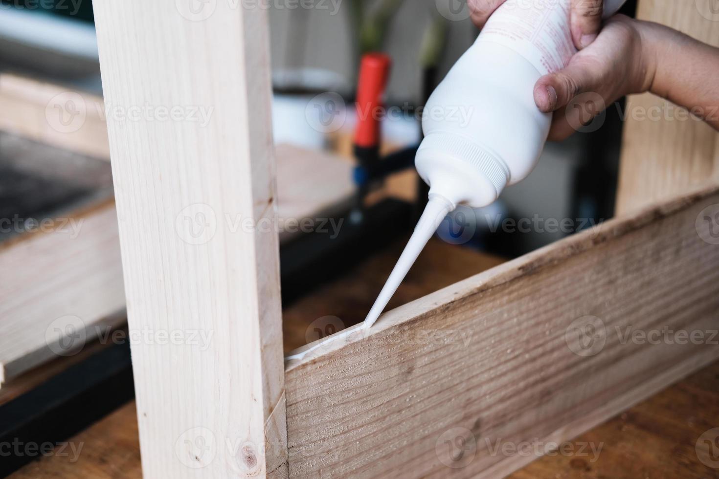 Woodworking operators are using glue to put together the wood parts to assemble and build a wooden table for their customers. photo