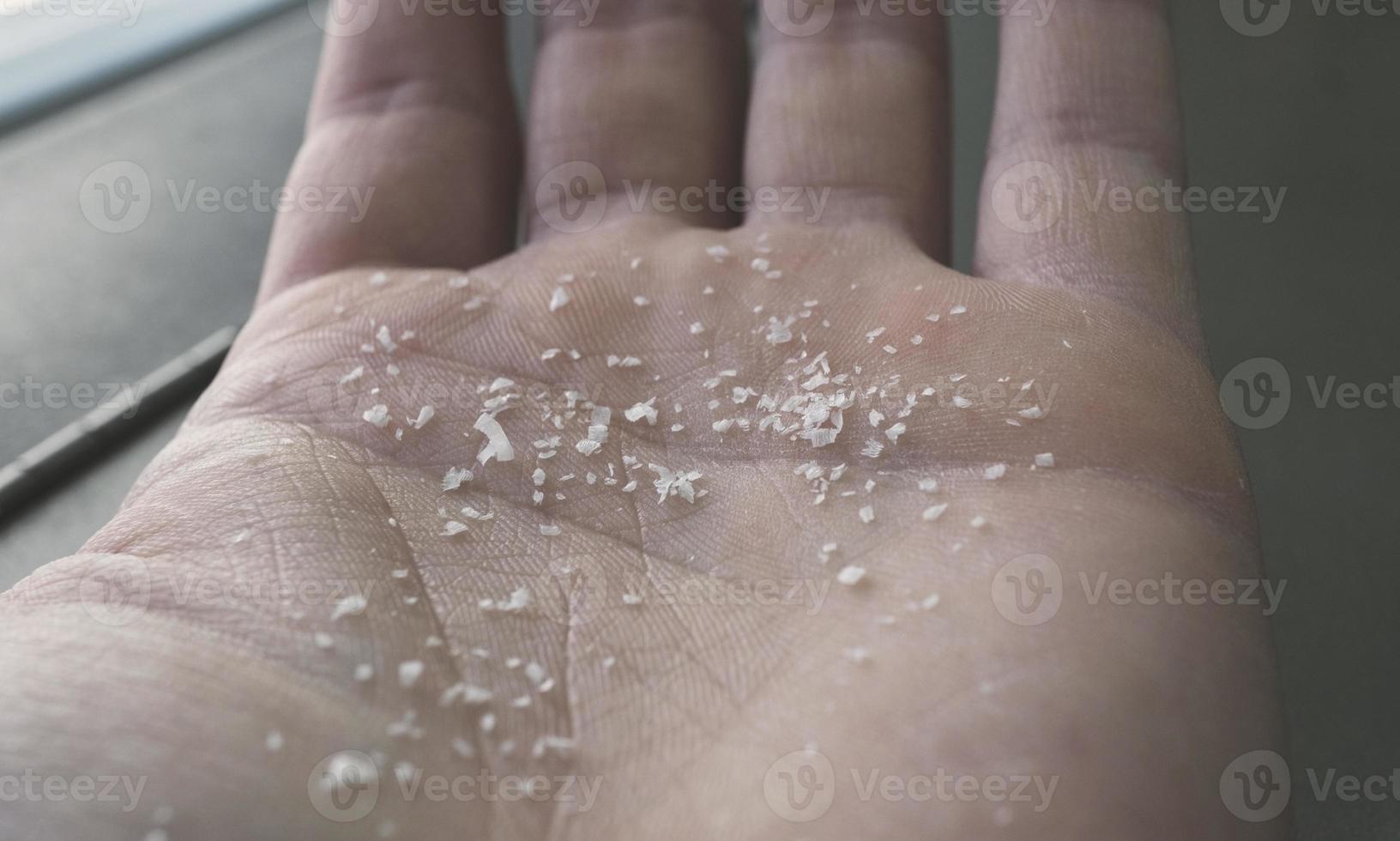 toma lateral de primer plano de microplásticos en los dedos humanos. concepto de contaminación del agua y calentamiento global. idea del cambio climático. enfoque suave en un montón de microplástico que no se puede reciclar. foto