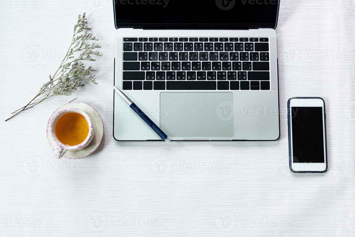 Work from home, workspace office at home, Notebook or laptop computer with pen mobile phone and Chinese tea cup  on the white desk at home office. photo