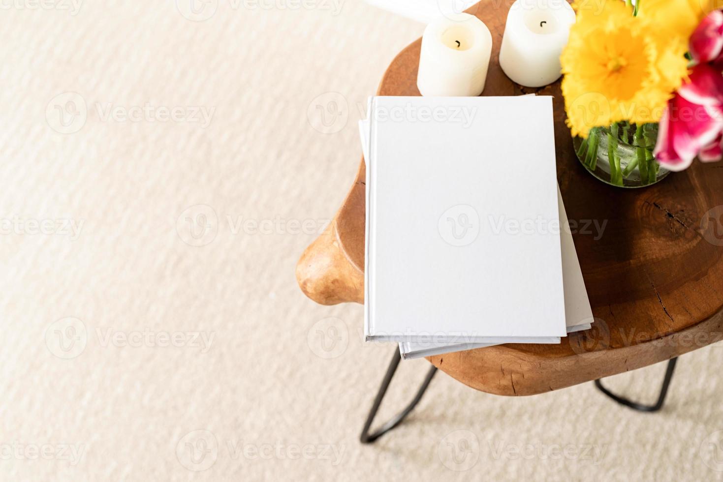White book blank cover mockup on stylish wooden coffee table with tulips bouquet, high angle view photo