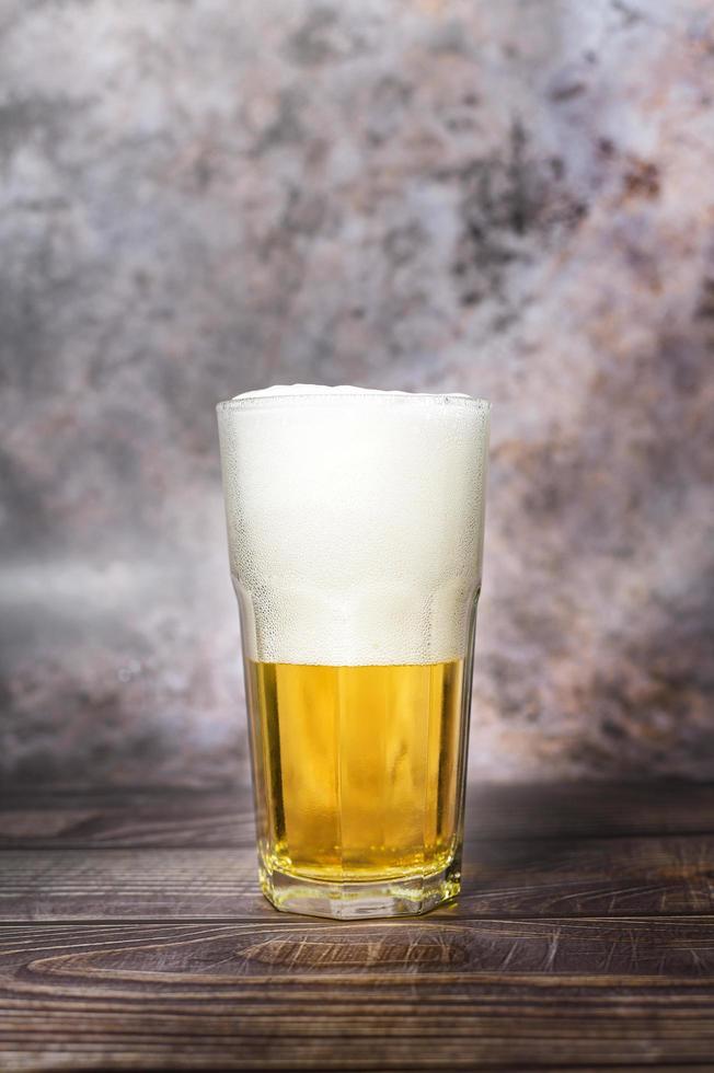 la cerveza ligera artesanal fría se vierte de la botella en la mesa de madera foto