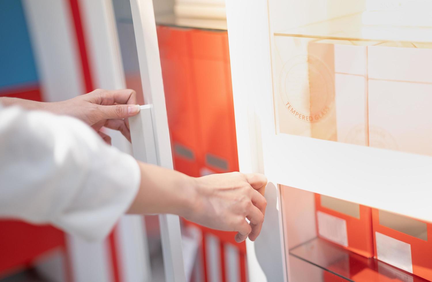 Female hand opening white document cupboard for choosing the document at the working office. photo