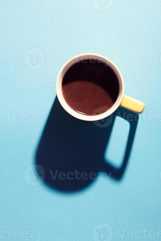 A cup of hot coffee in pastel colors. Turkish coffee in a yellow mug on blue background. photo