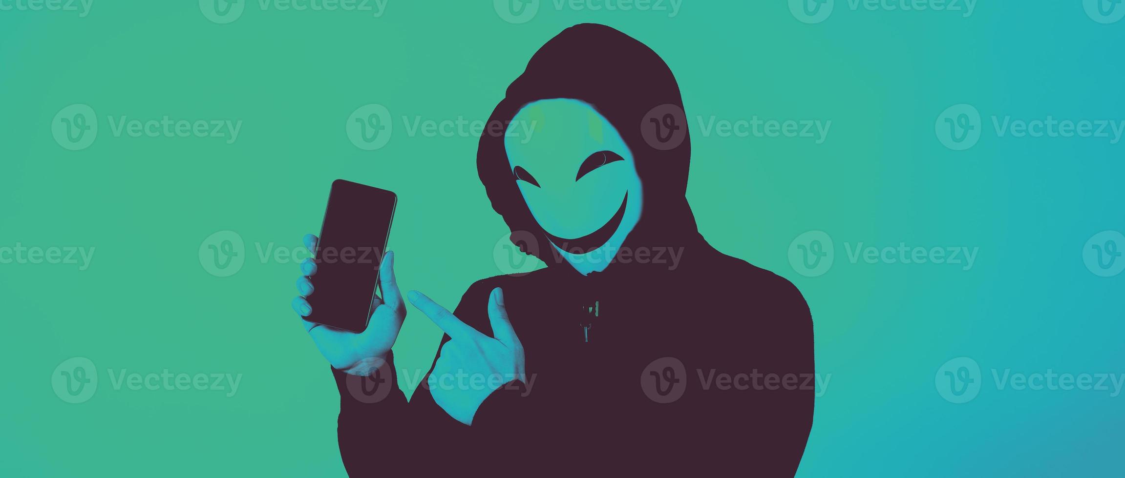 Anonymous hacker and face mask with smartphone in hand. photo