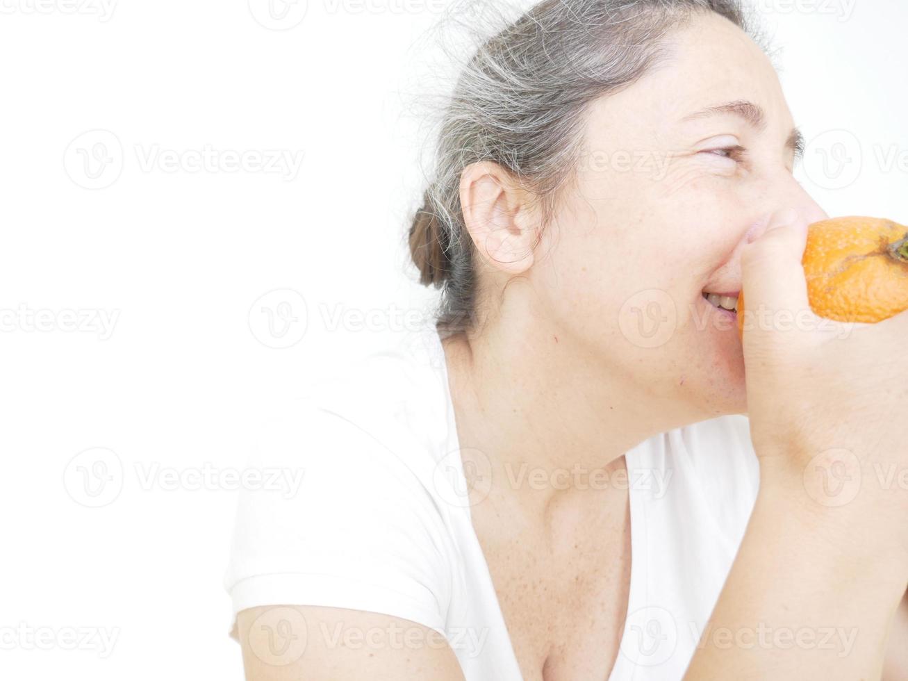 Forty nine year old woman in a white T-Shirt against a white background with an orange photo