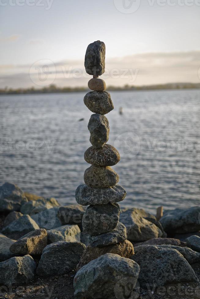 The art of Rock balancing with water, clouds and sky in the background photo